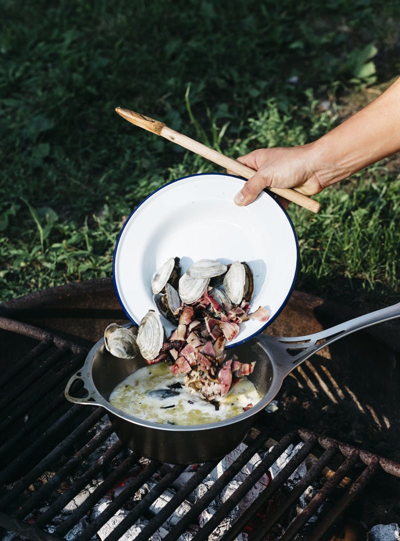 Adding cooked clams and bacon into the cooking liquid to start the soup.