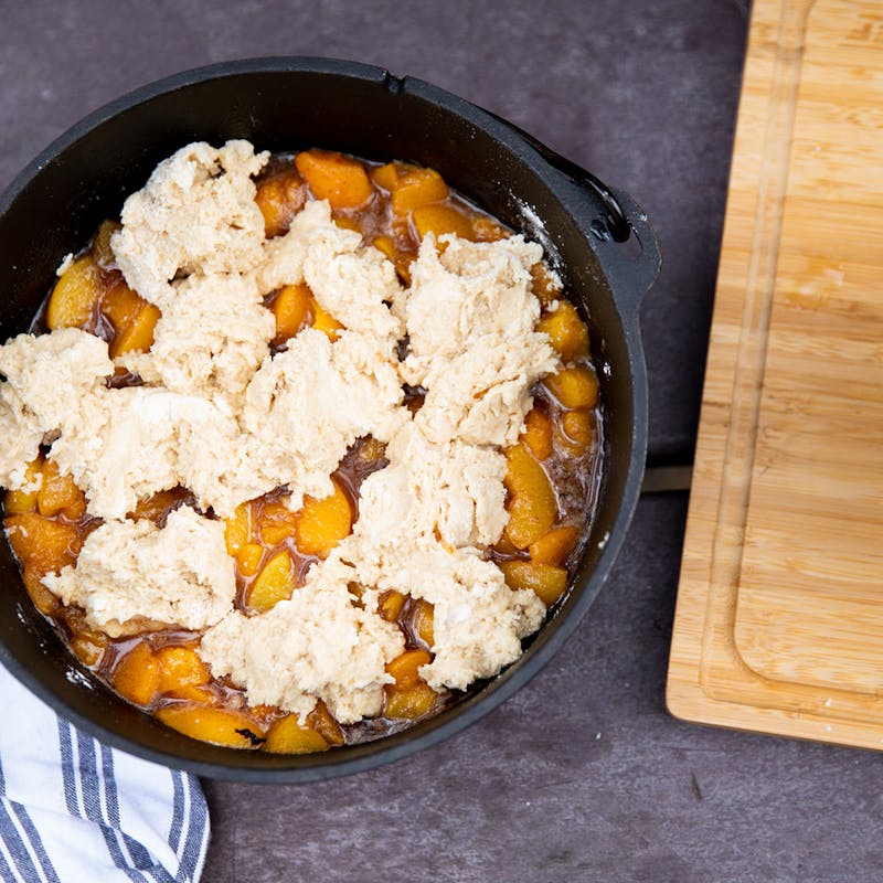 Peach cobbler assembled in a dutch oven and ready to bake.