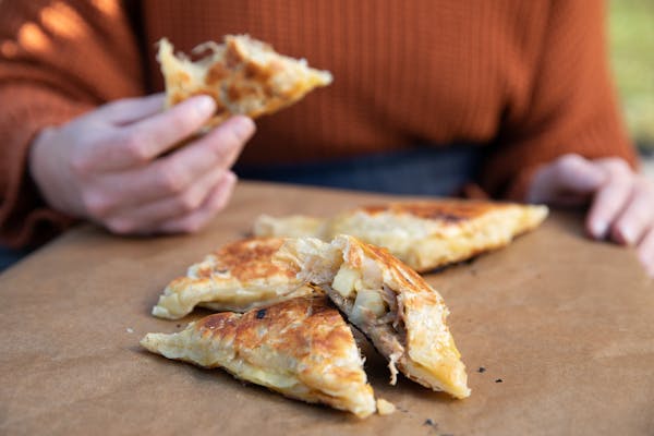 A hand holding a hand pie with a bite taken out of it.