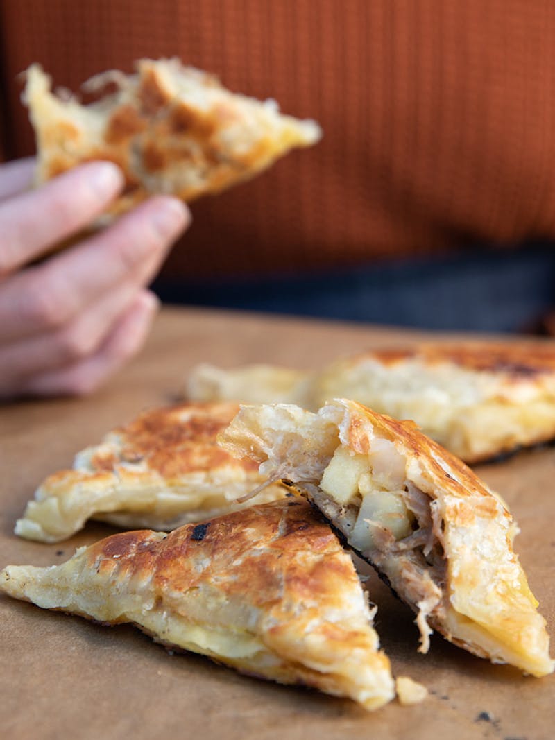 A hand holding a hand pie with a bite taken out of it.