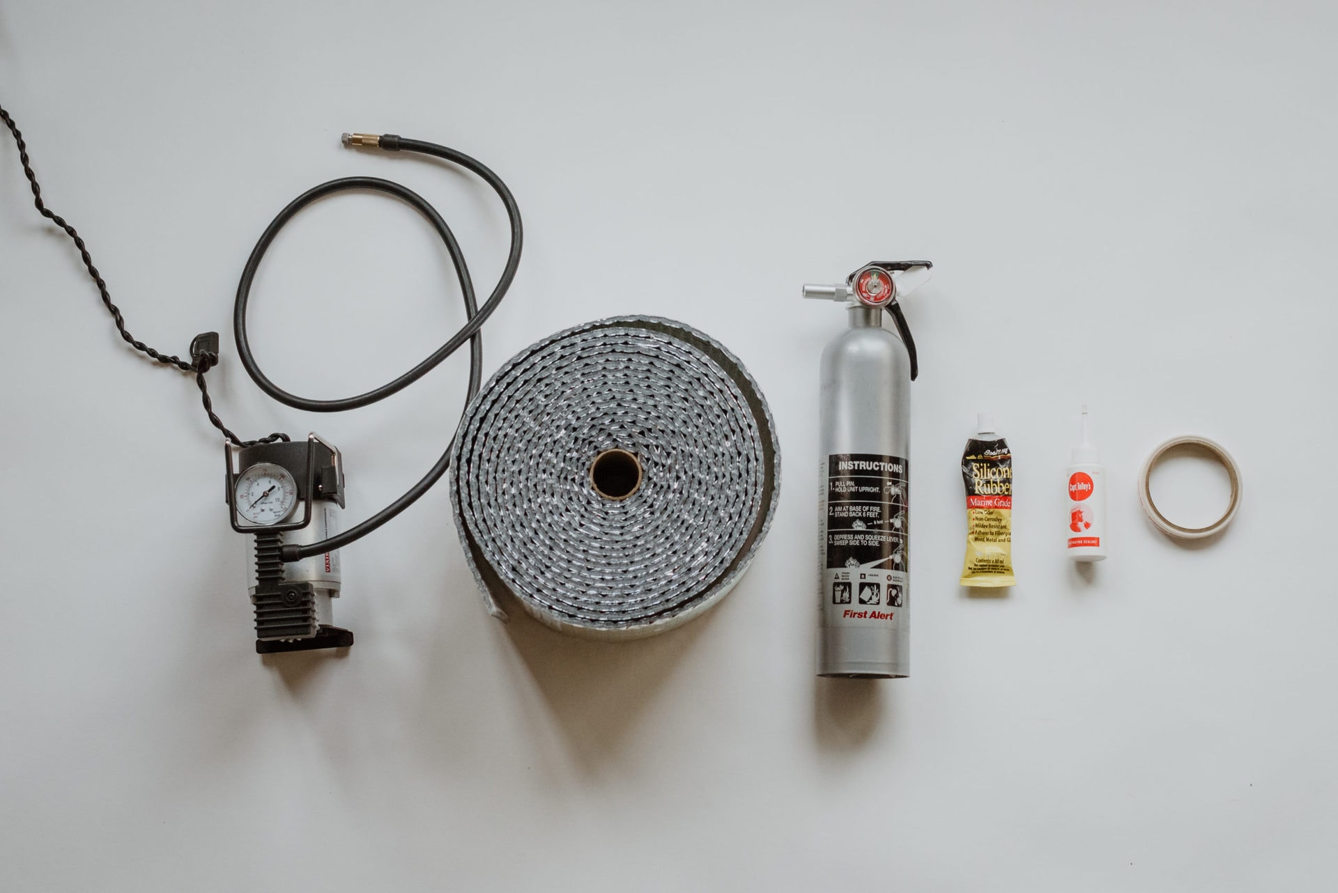 Shot of various RV essential items, including tire pressure gauge, fire extinguisher, glue and tape