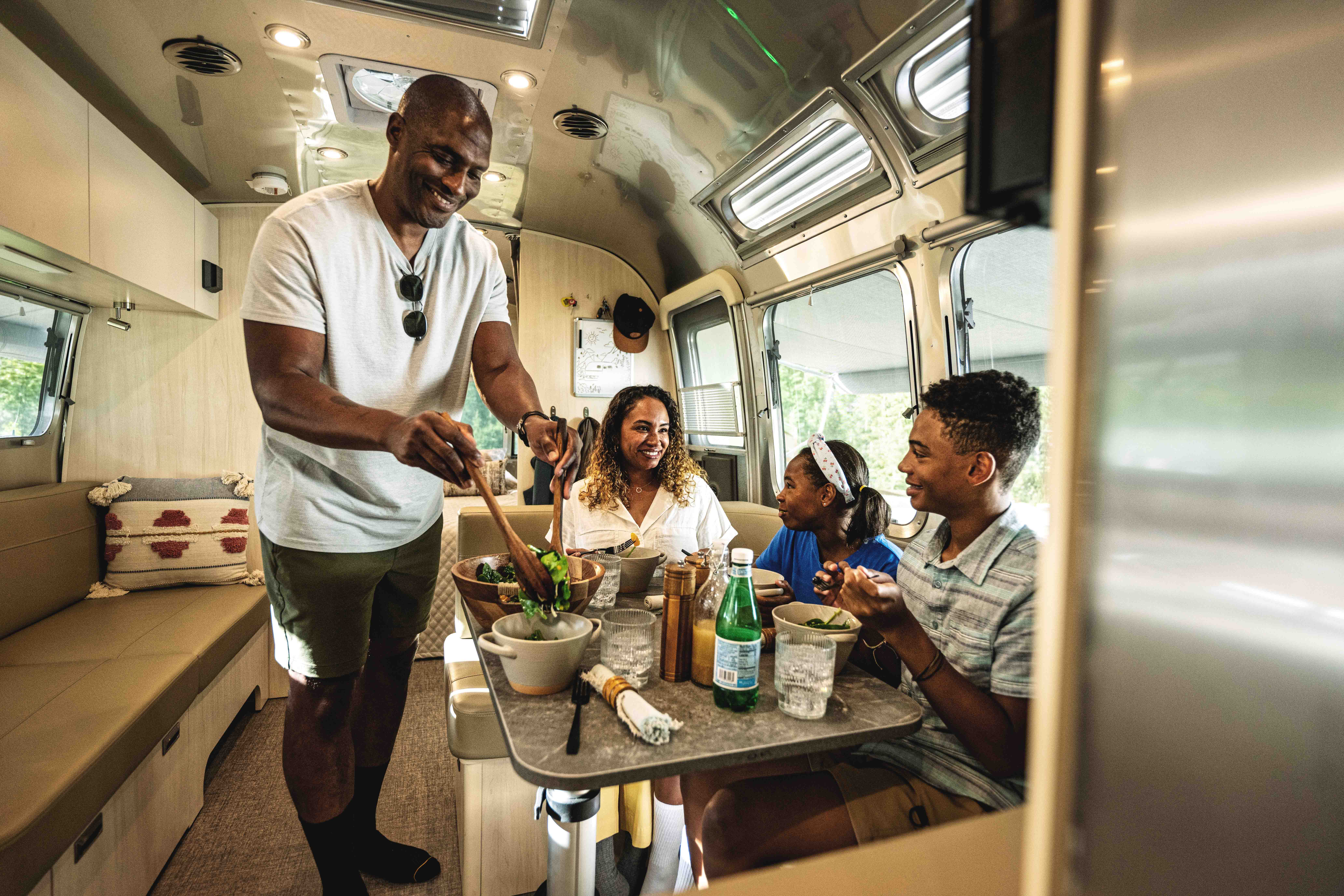 A family enjoys a meal at the dinette inside a Airstream Flying Cloud.