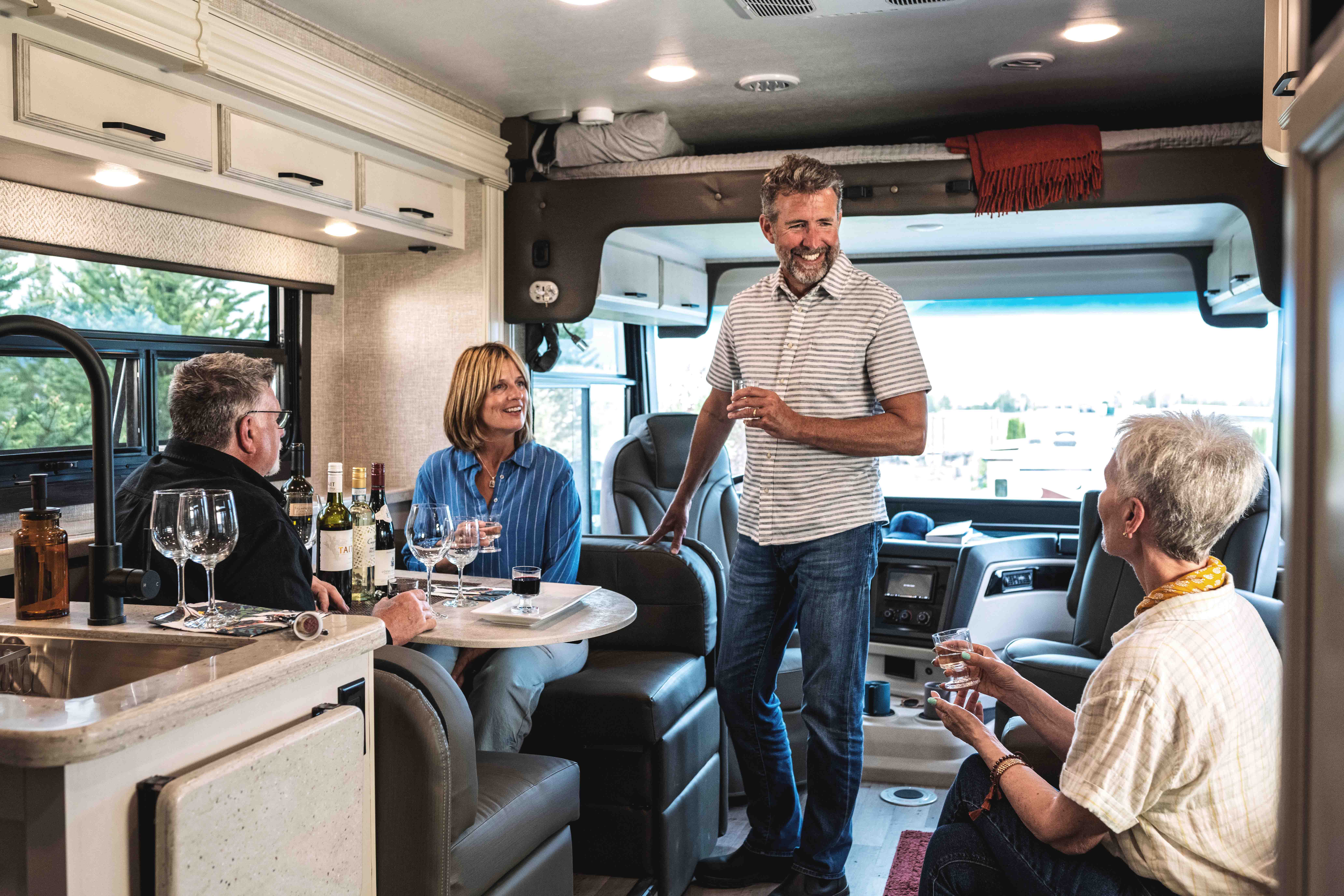 A group of friends enjoy drinks together inside a Entegra Vision Class A motorhome.