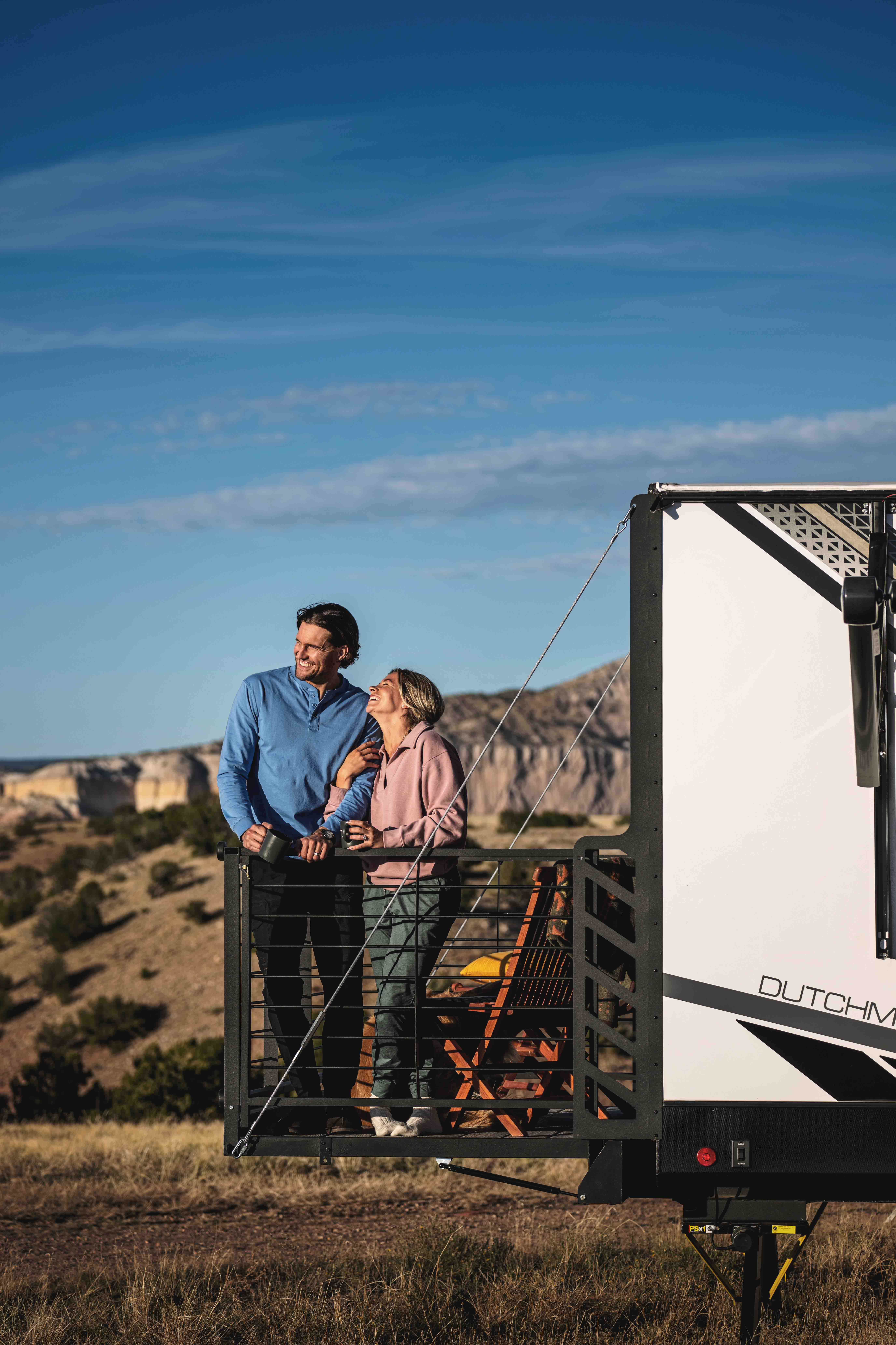 A couple stands on the porch of a Dutchmen Kodiak.