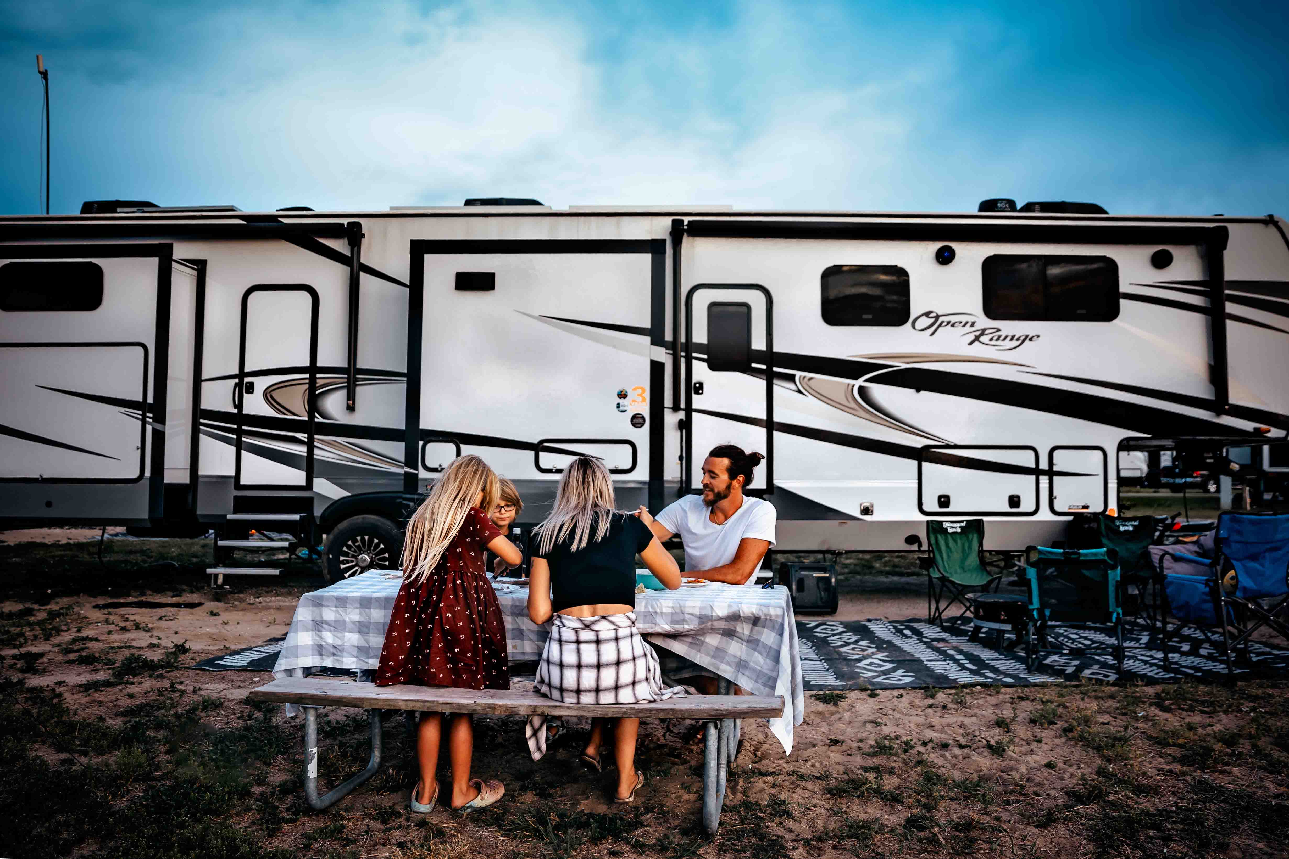 The Bailey family sits at a picnic table next to their Highland Ridge Open Range.