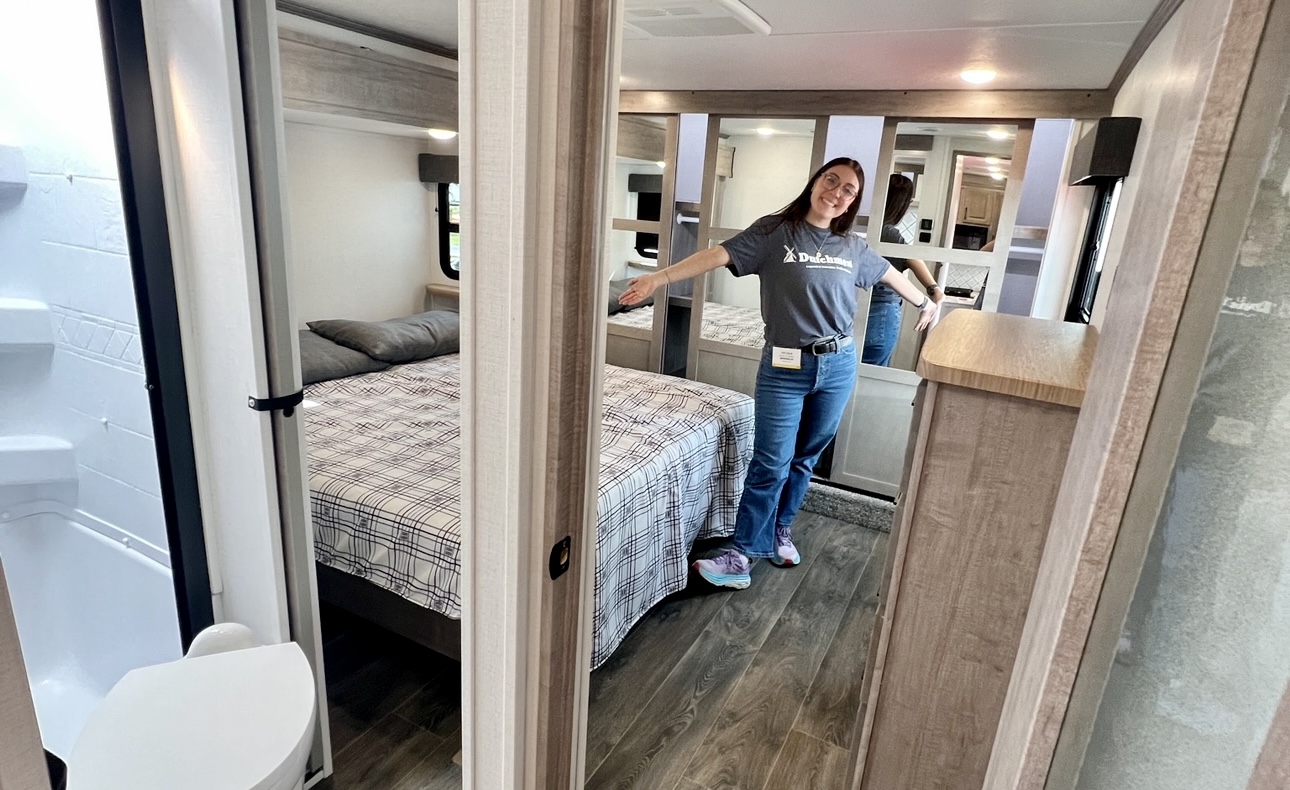 Nicole Damberg showing off a large bedroom in an RV at an early spring RV show.