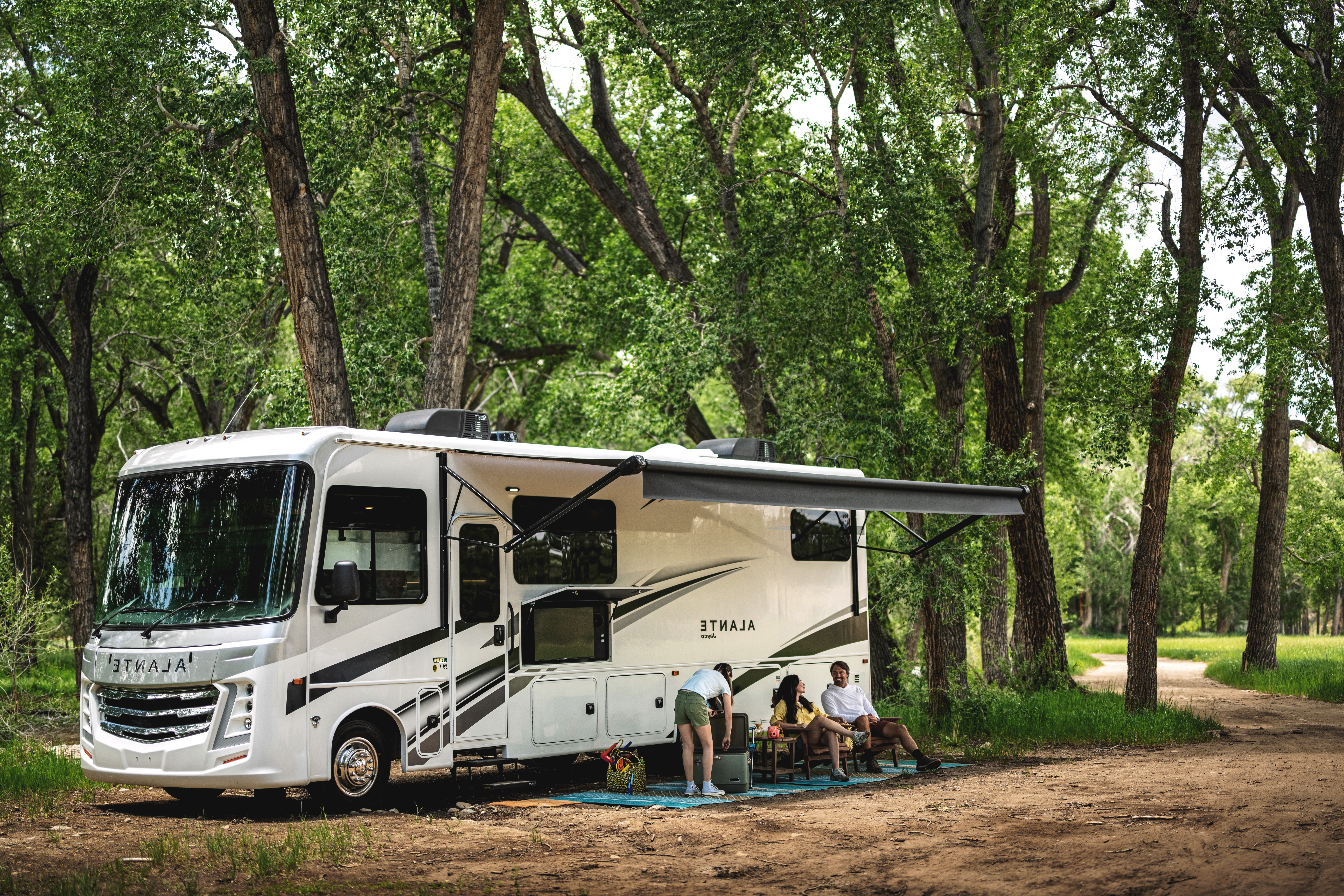 A family sits in front of a Jayco Alante Class A Motorhome.