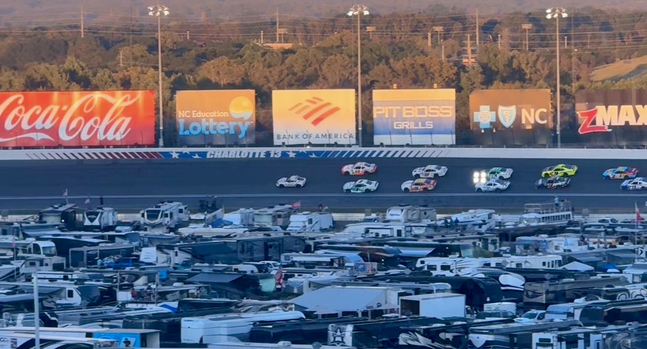 Race cars on the track circling the infield RV camping at the Charlotte Motor Speedway.