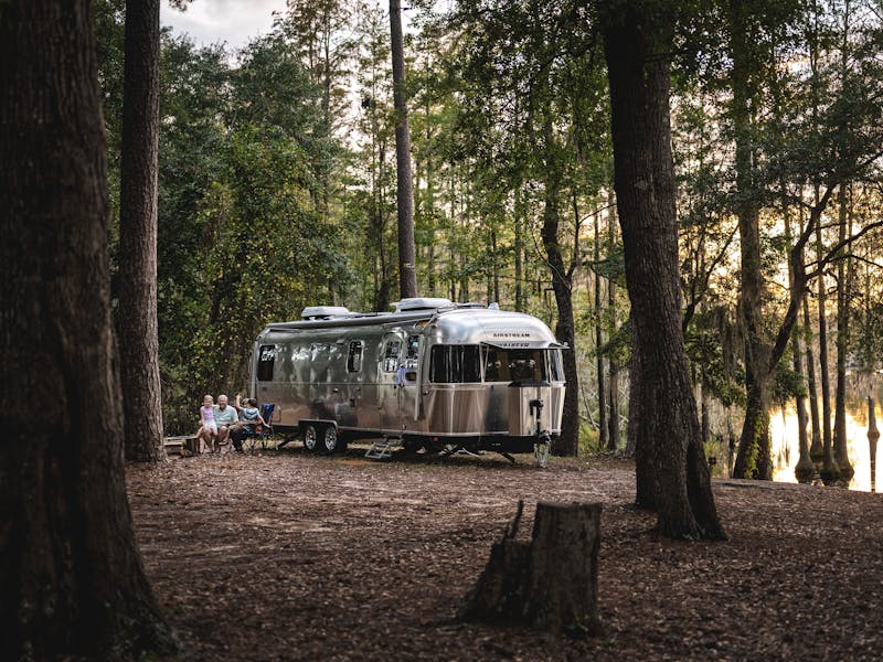 An Airstream travel trailer parked in the woods.