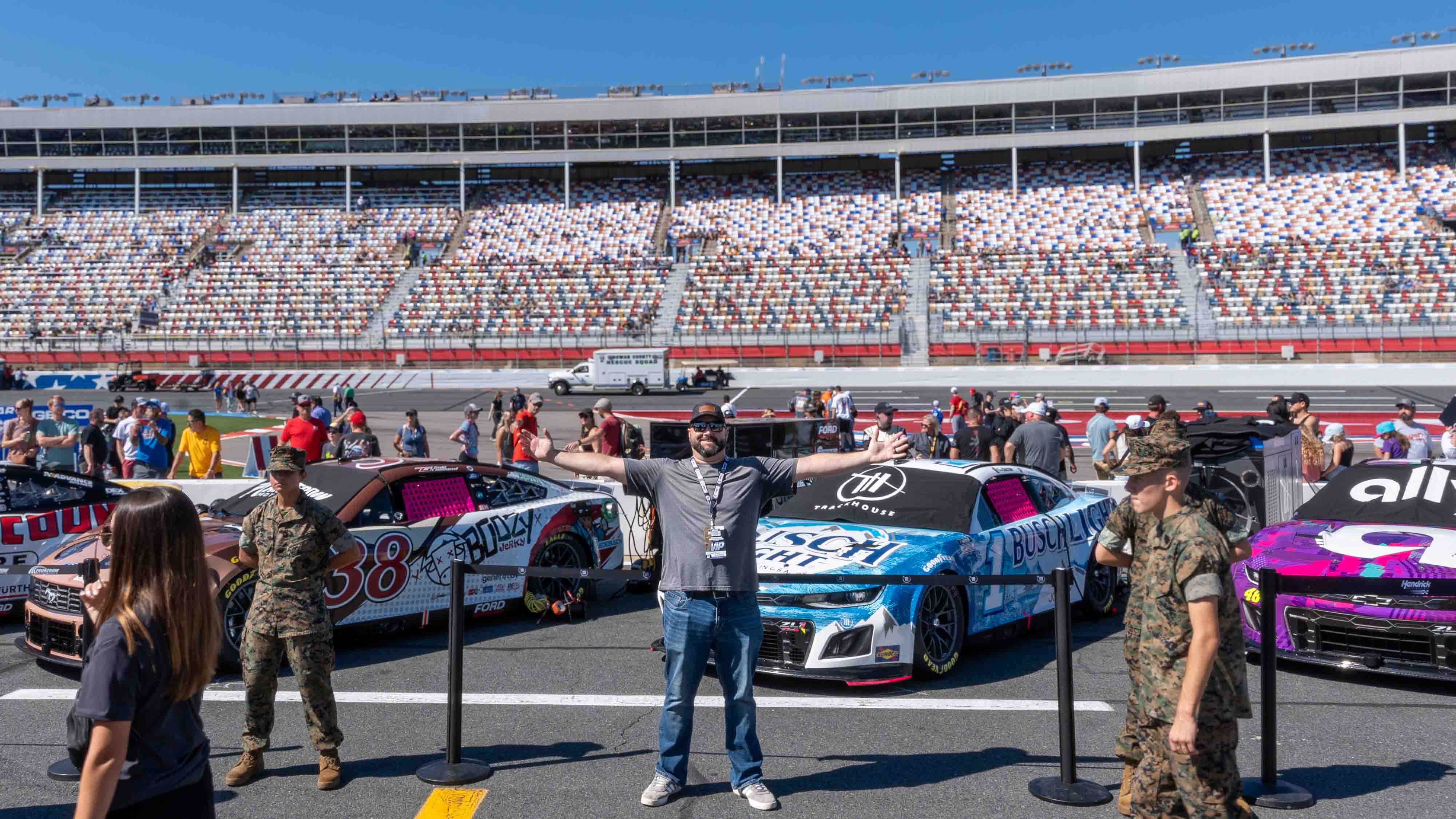 Gabe Rivero next to race cars as a NASCAR race.