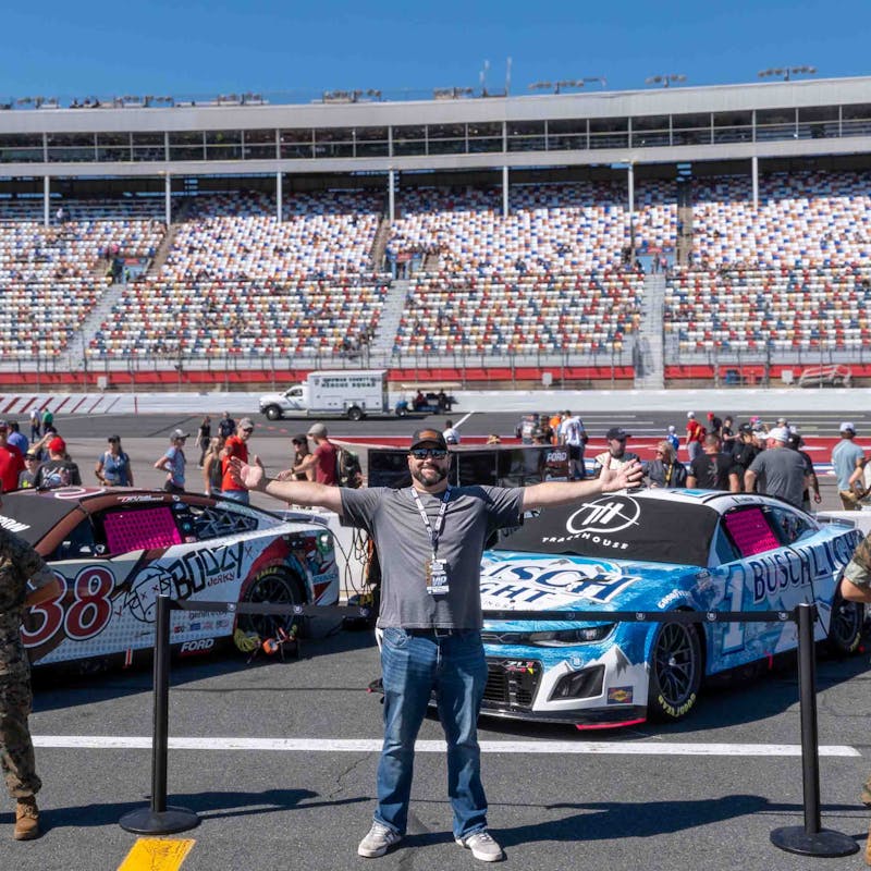 Gabe Rivero next to race cars as a NASCAR race.