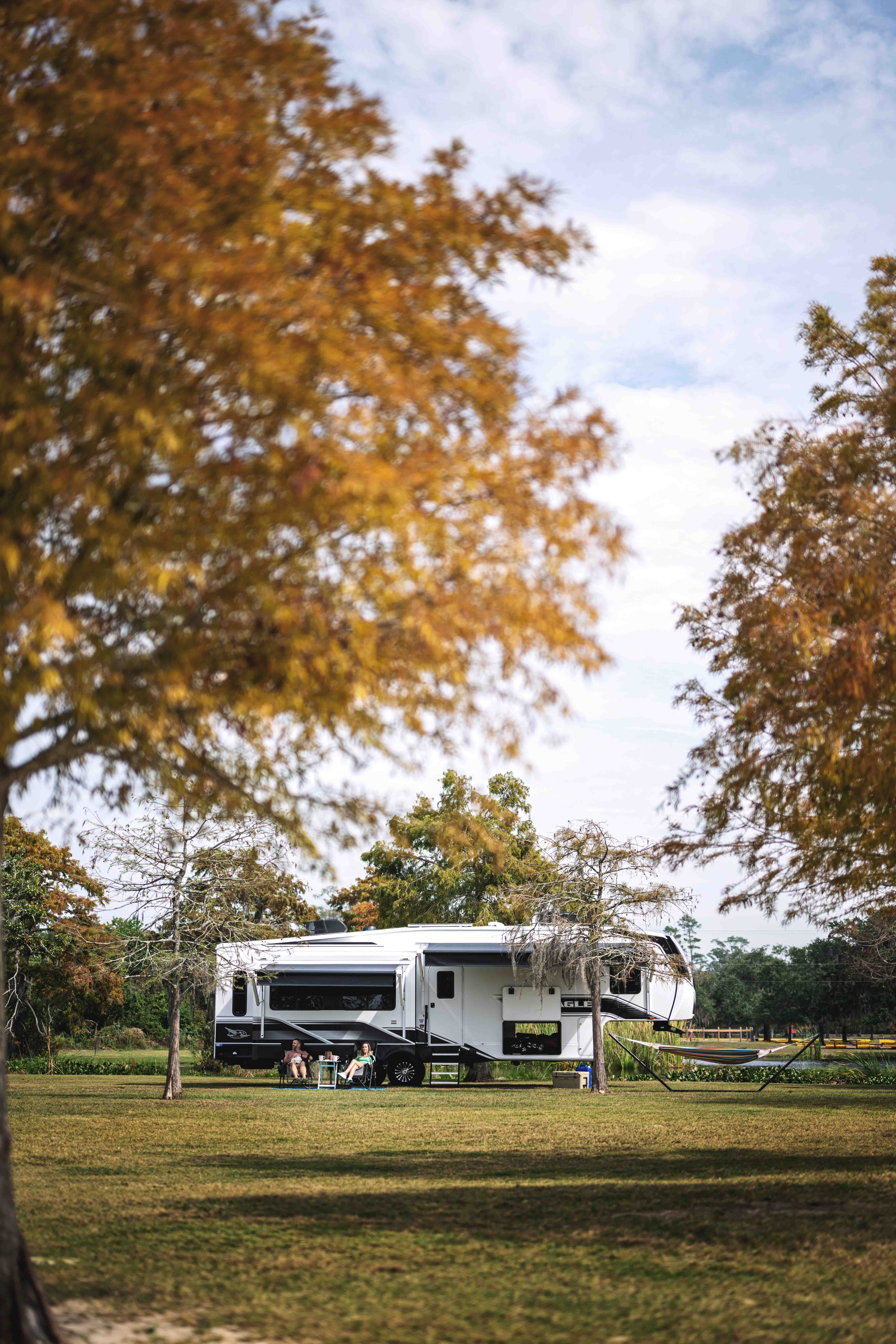 A Jayco Eagle fifth wheel camping among trees.