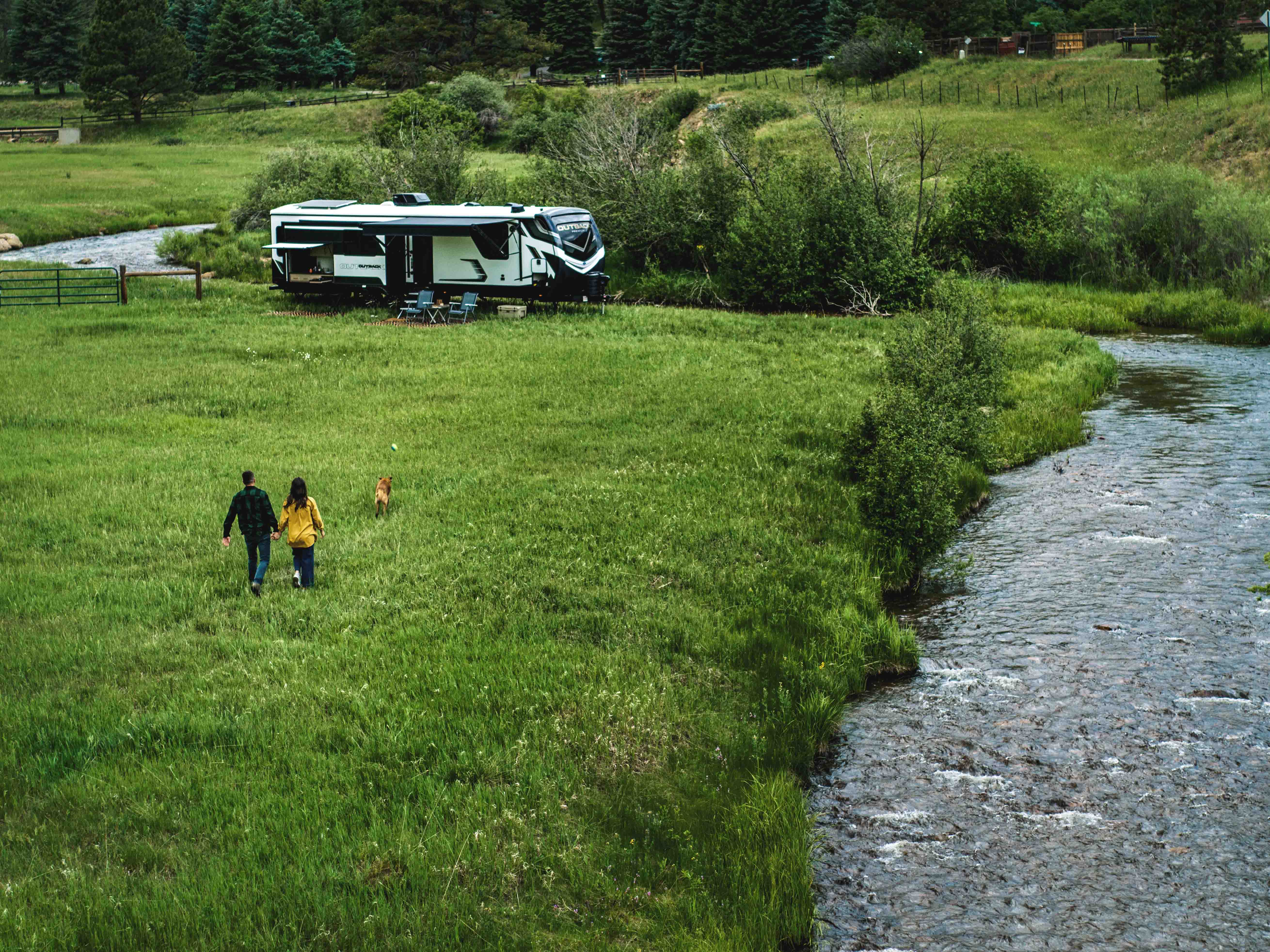 A couple walks next to a Keystone Outback travel trailer.
