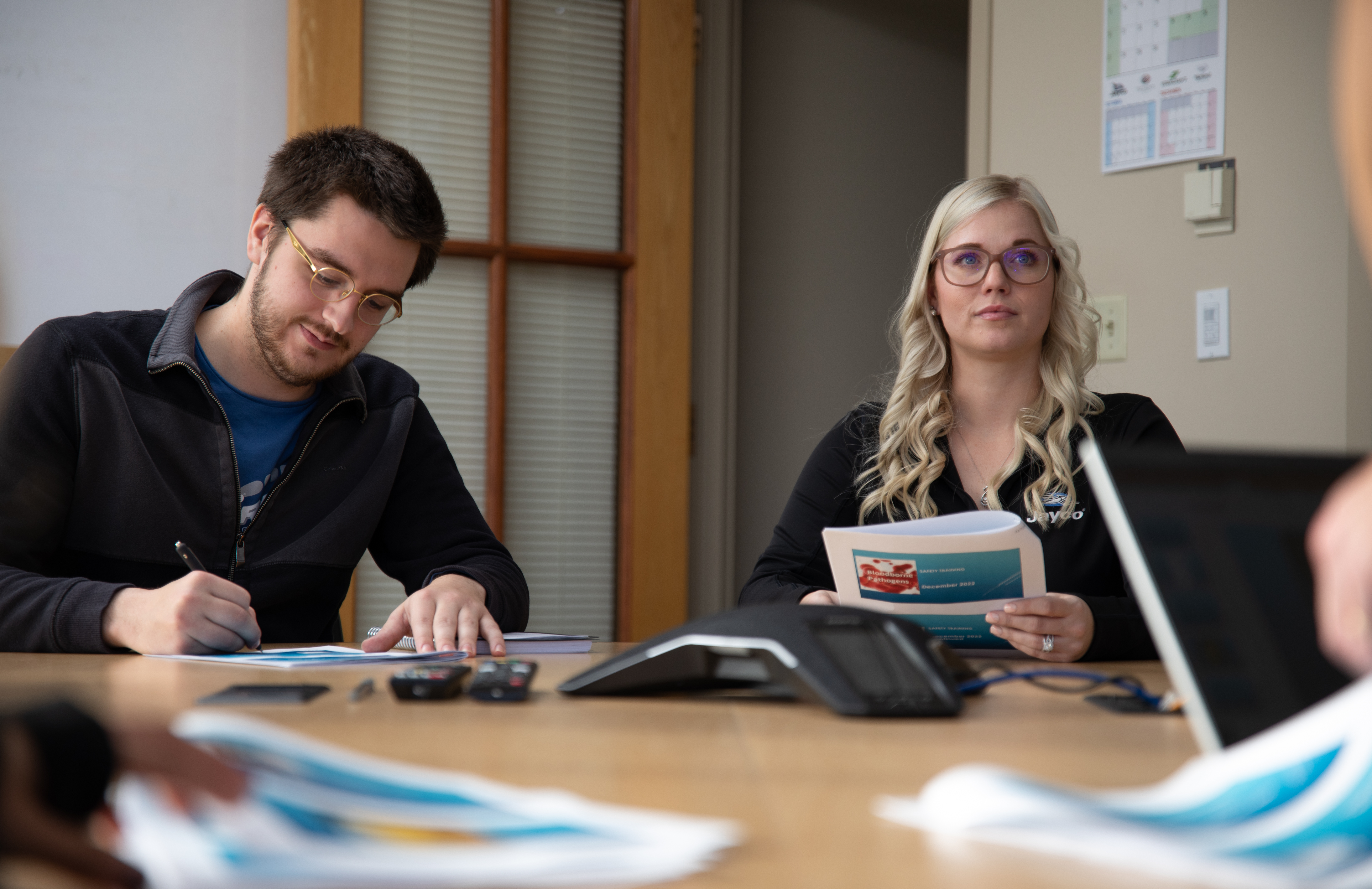 A man and a woman work at a table during a business meeting.