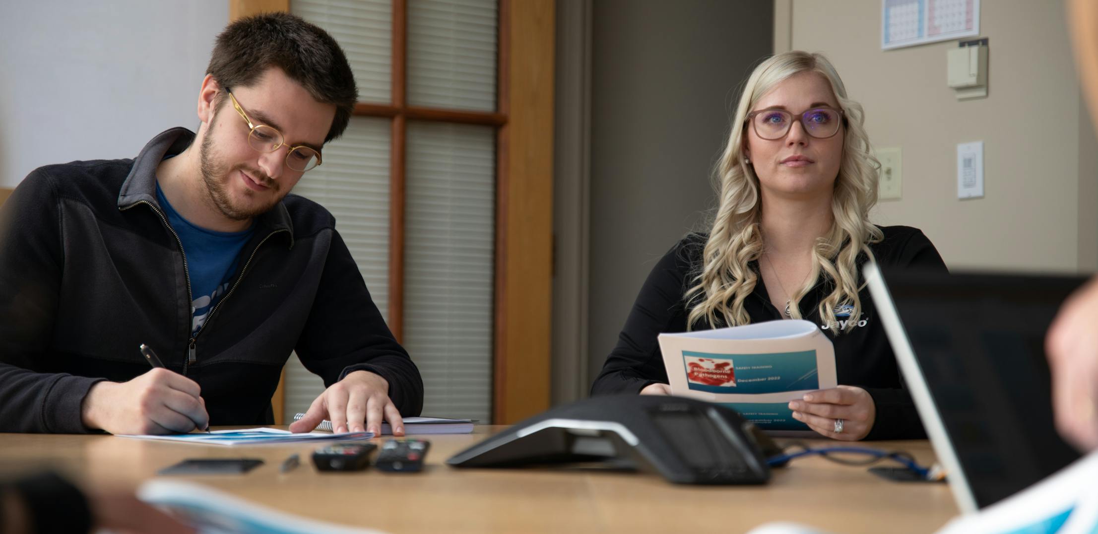 A man and a woman work at a table during a business meeting.