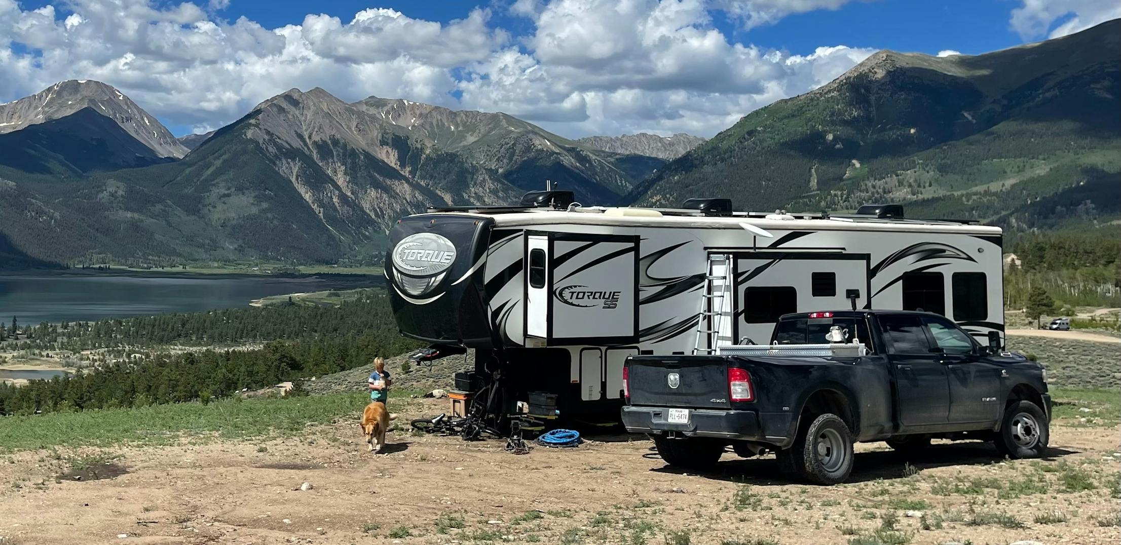 Melissa and Lucas Lahr's Heartland Torque toy hauler at a scenic lookout featuring mountains  and cloudy skies.