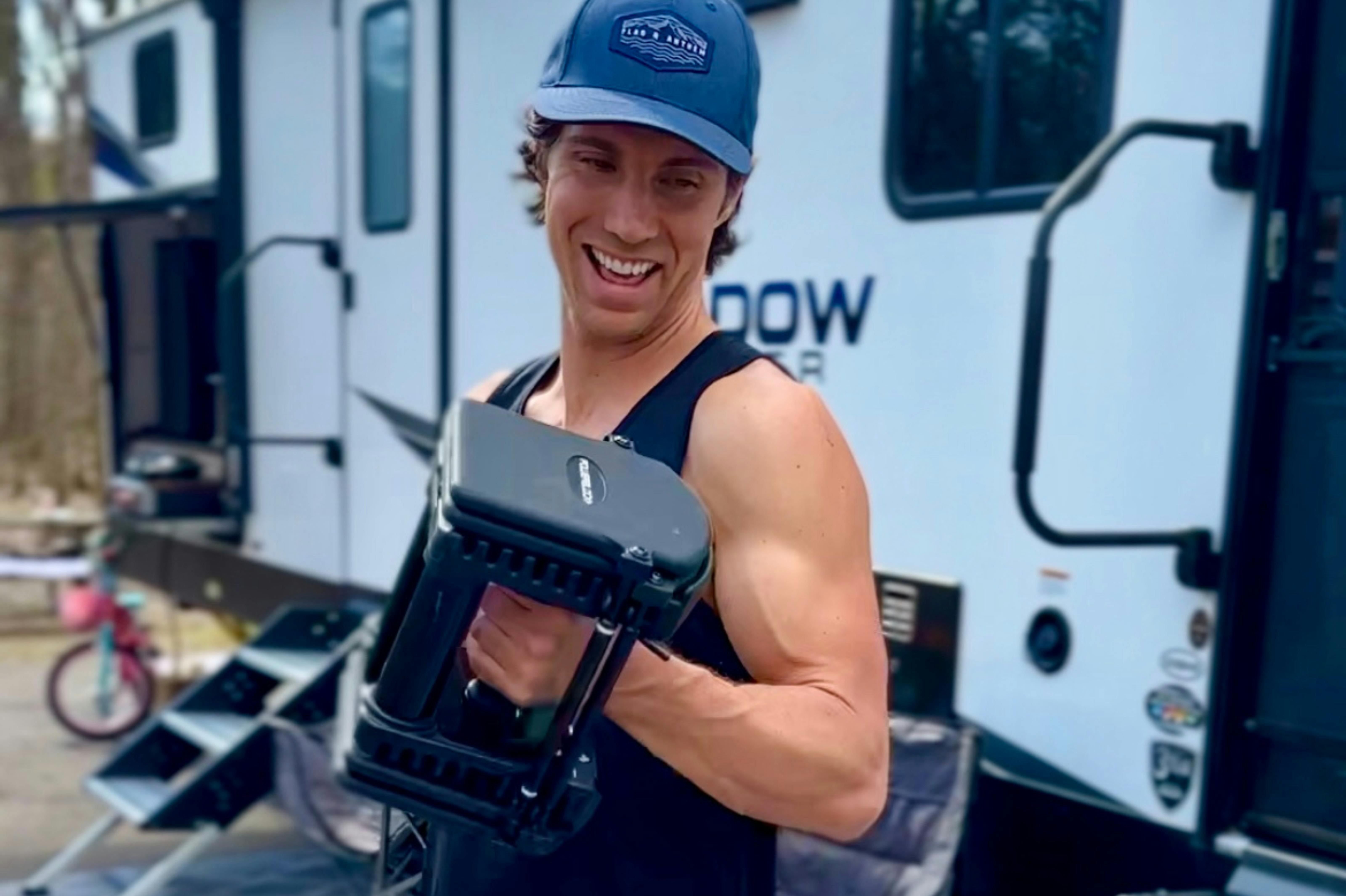 John King lifting weights outside of his Shadow Cruiser travel trailer.