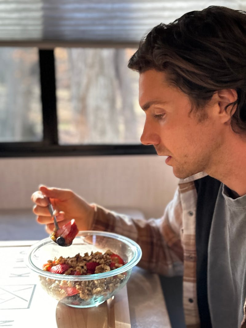 John King eating a fruit bowl inside his Shadow Cruiser travel trailer.