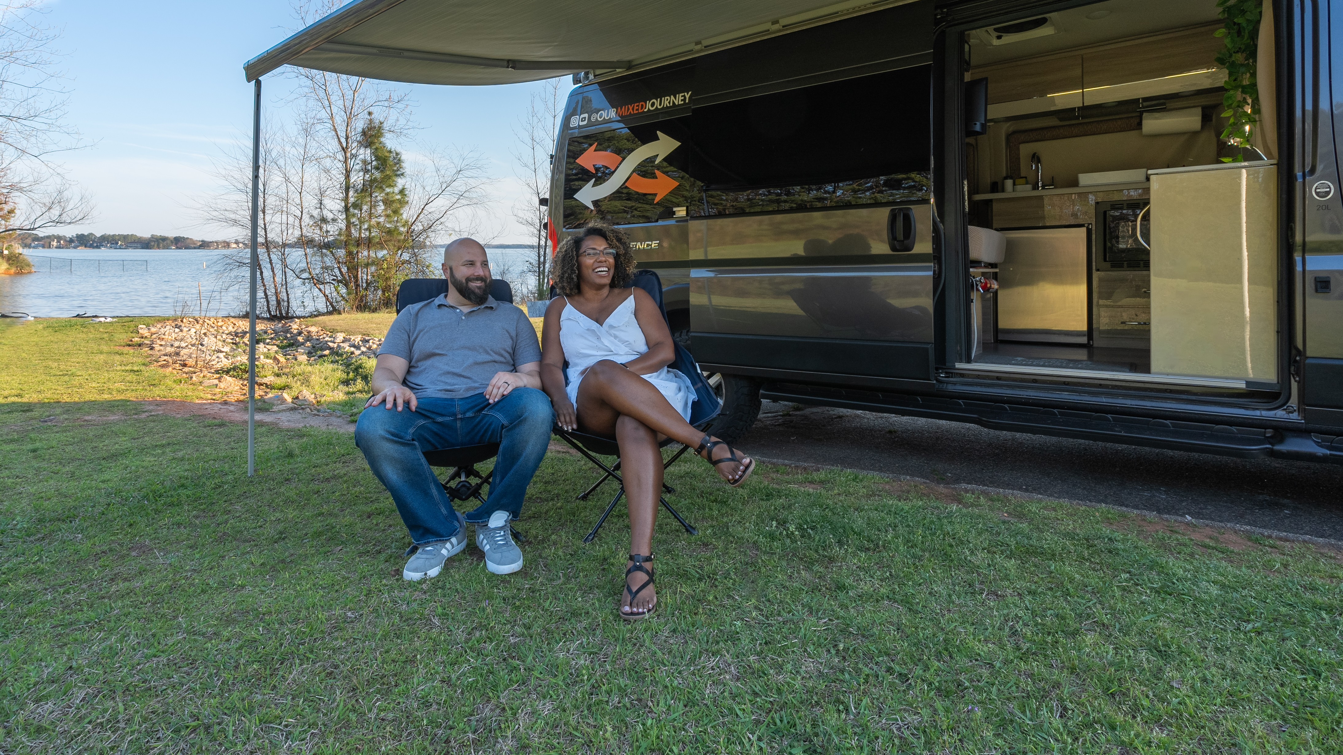 Gabe and Rocio Rivero lounge by the lake under a built-in awning of their Thor Motor Coach Sequence.