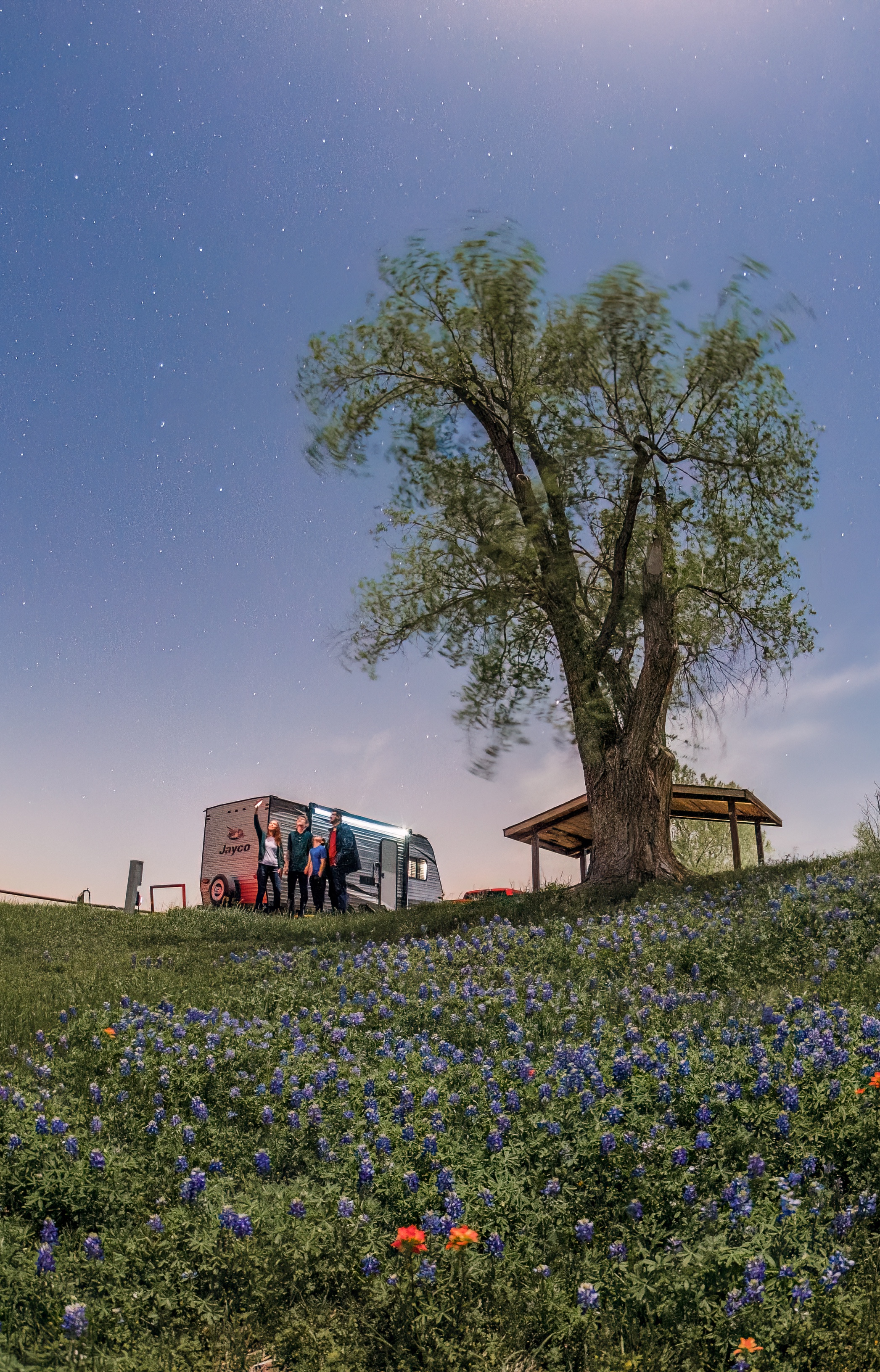 The Jason and Alison Takacs family look to the sky in a field of Bluebonnets next to their Jayco Jay Flight travel trailer.