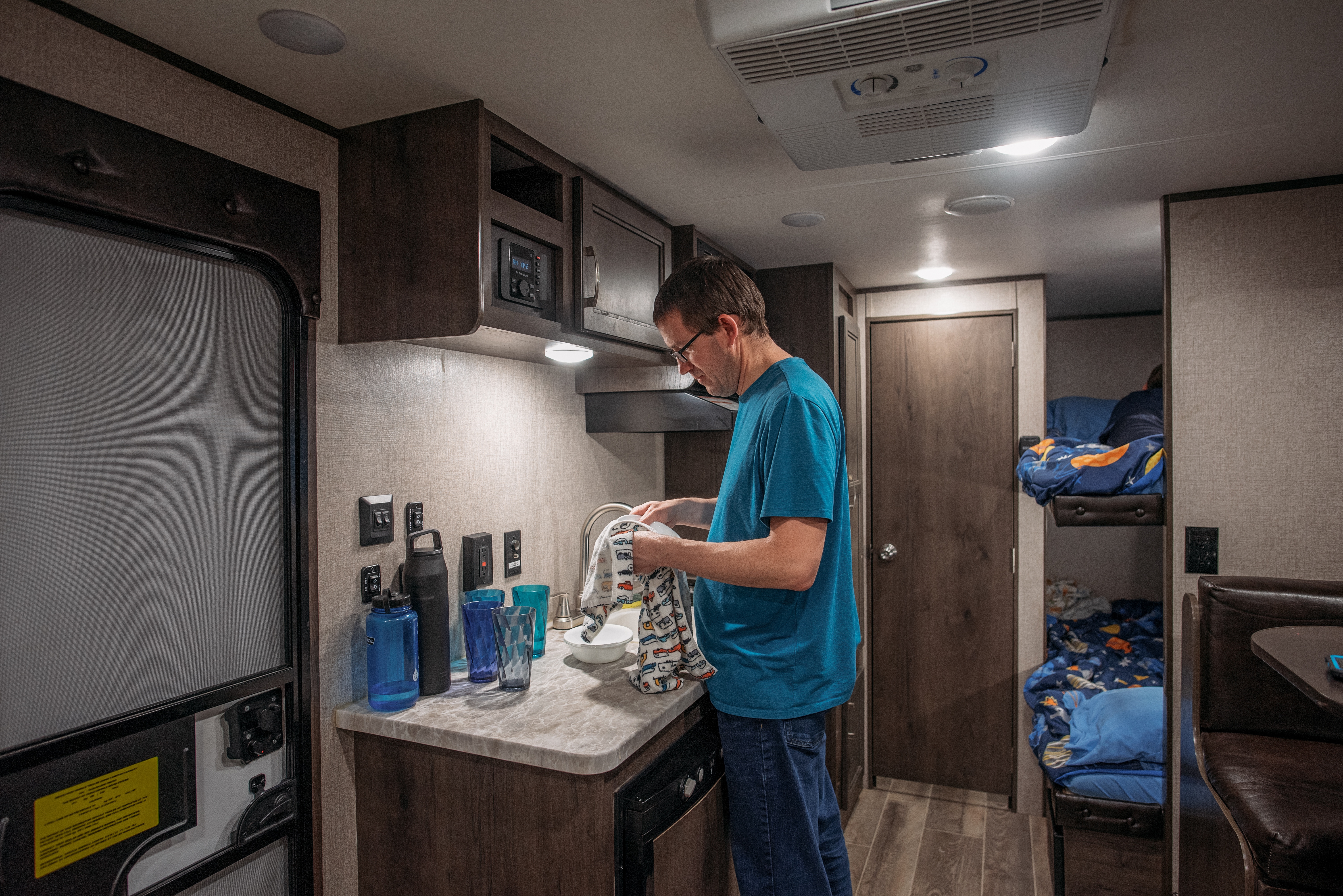 Jason Takacs does the dishes inside his Jayco Jay Flight travel trailer.