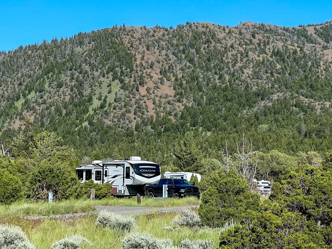 Donny and Tammy Benedict's Keystone Cougar parked in a valley near the mountains.