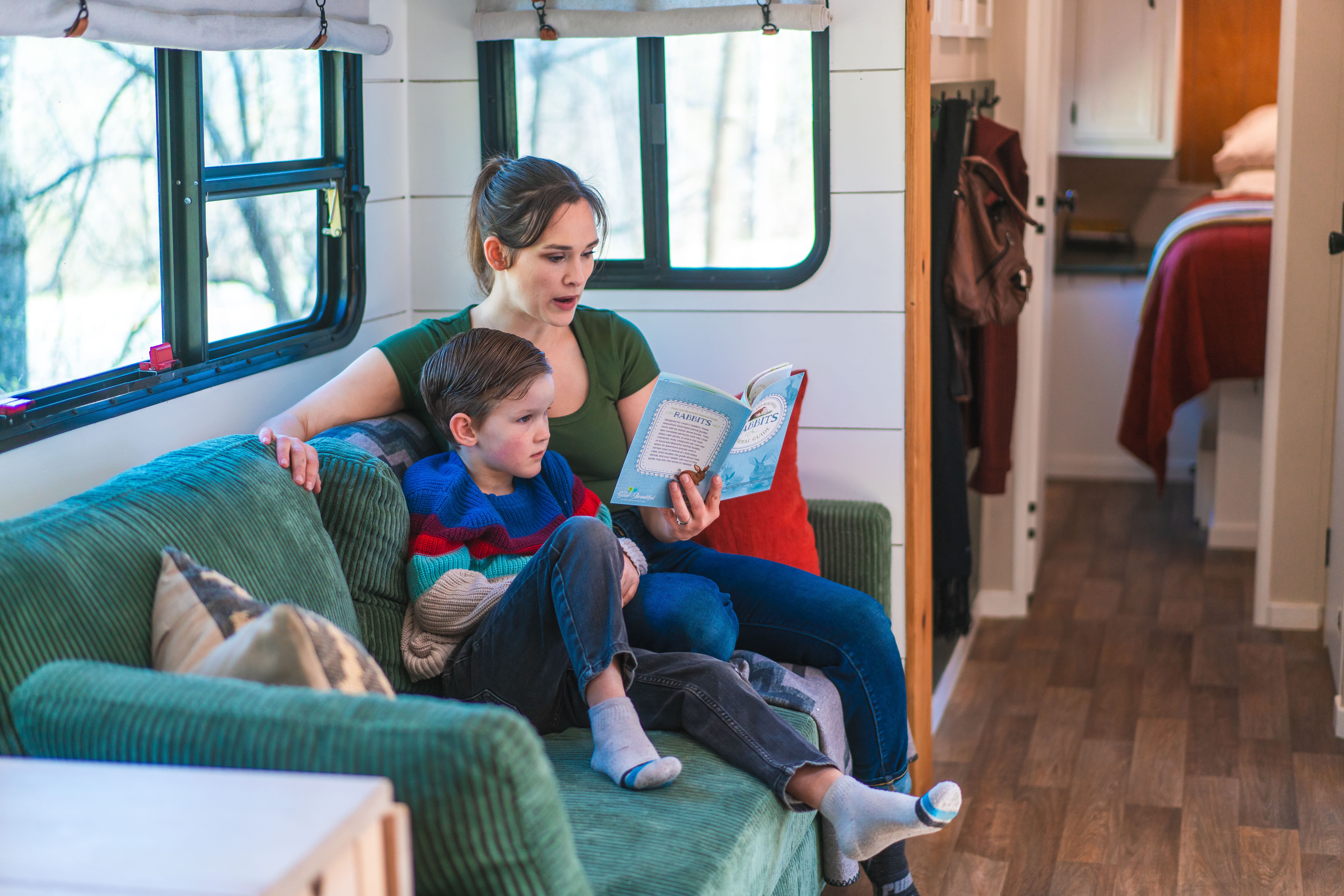 Renee Tilby reads to her son on the couch inside their Jayco Jay Flight travel trailer.