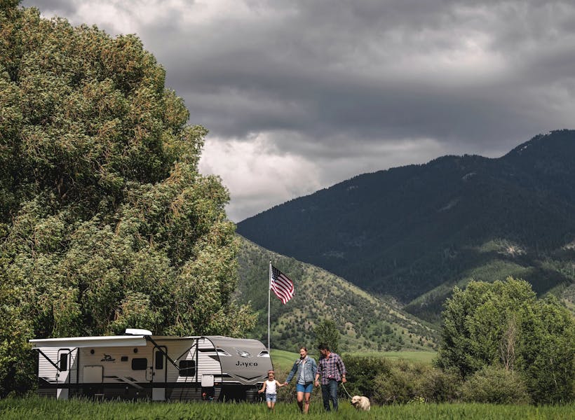 a family walking away from a jayco jay flight travel trailer camping in the mountains