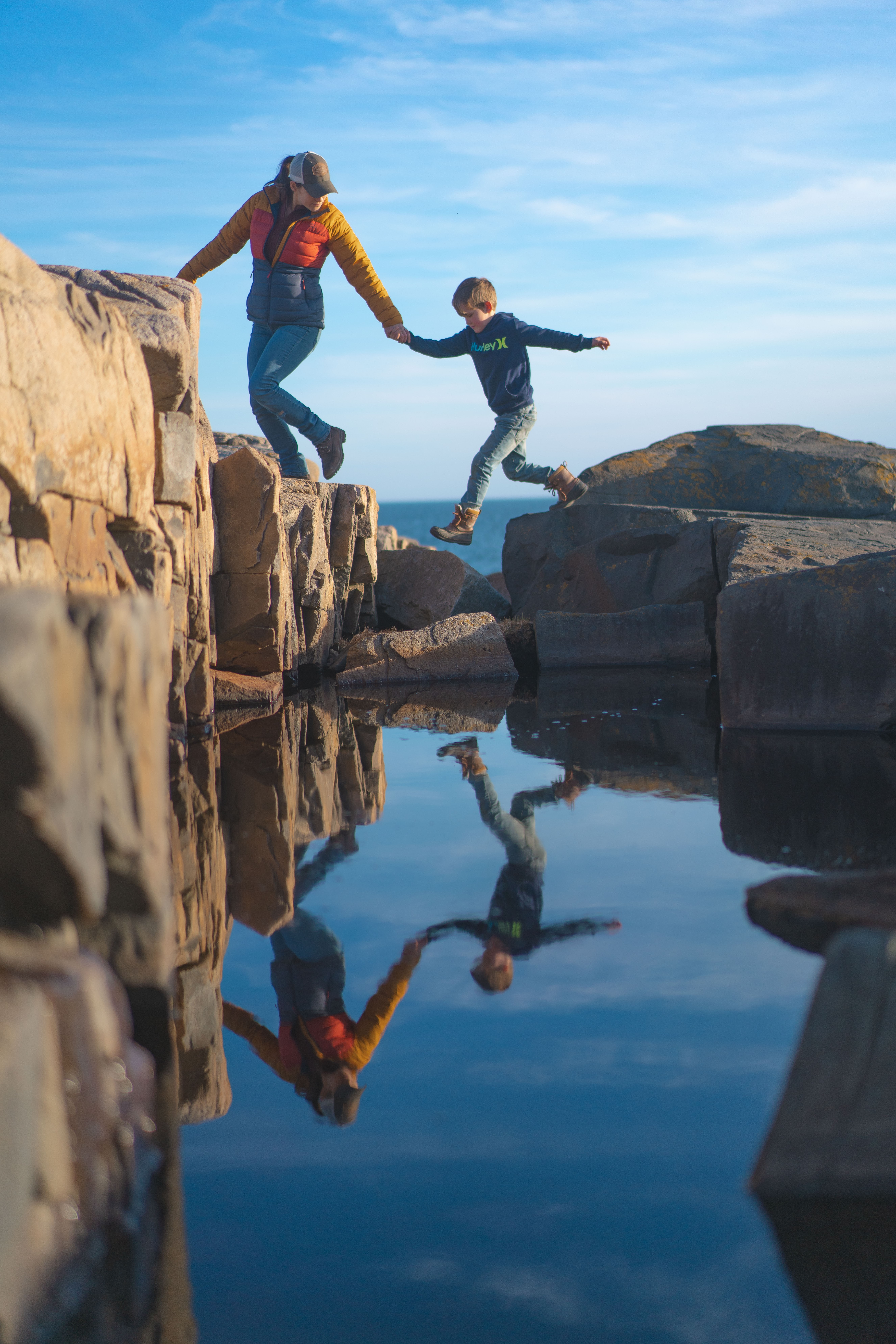 Renee Tilby and her kid climb rocks in Maine.