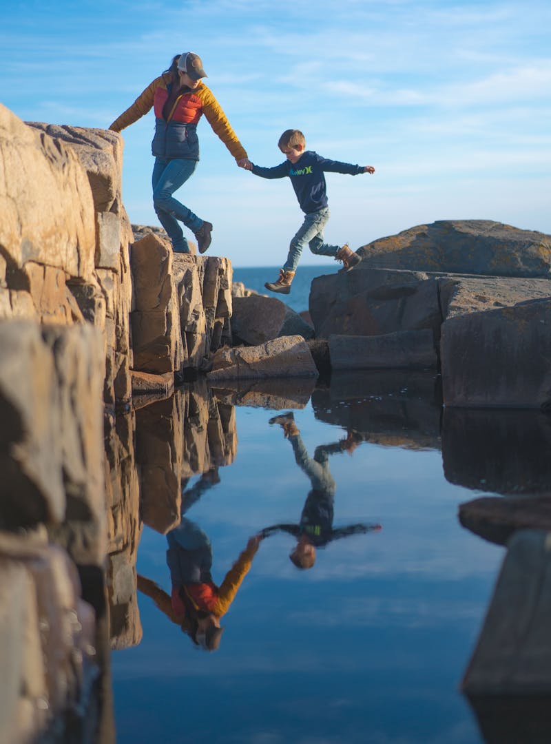 Renee Tilby and her kid climb rocks in Maine.