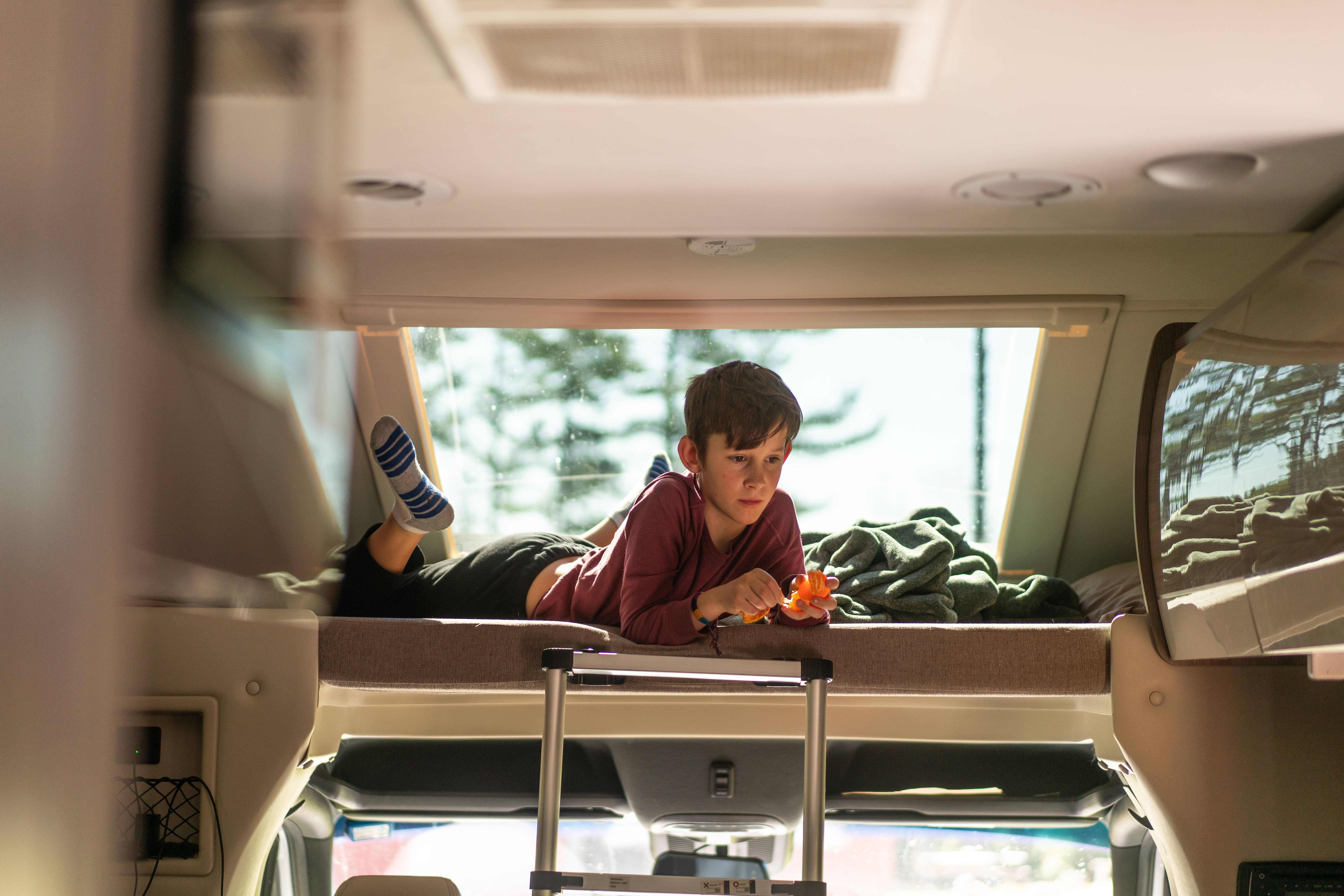 One of the Tilby kids sits in the overhead bunkbed in a rented motorized RV.