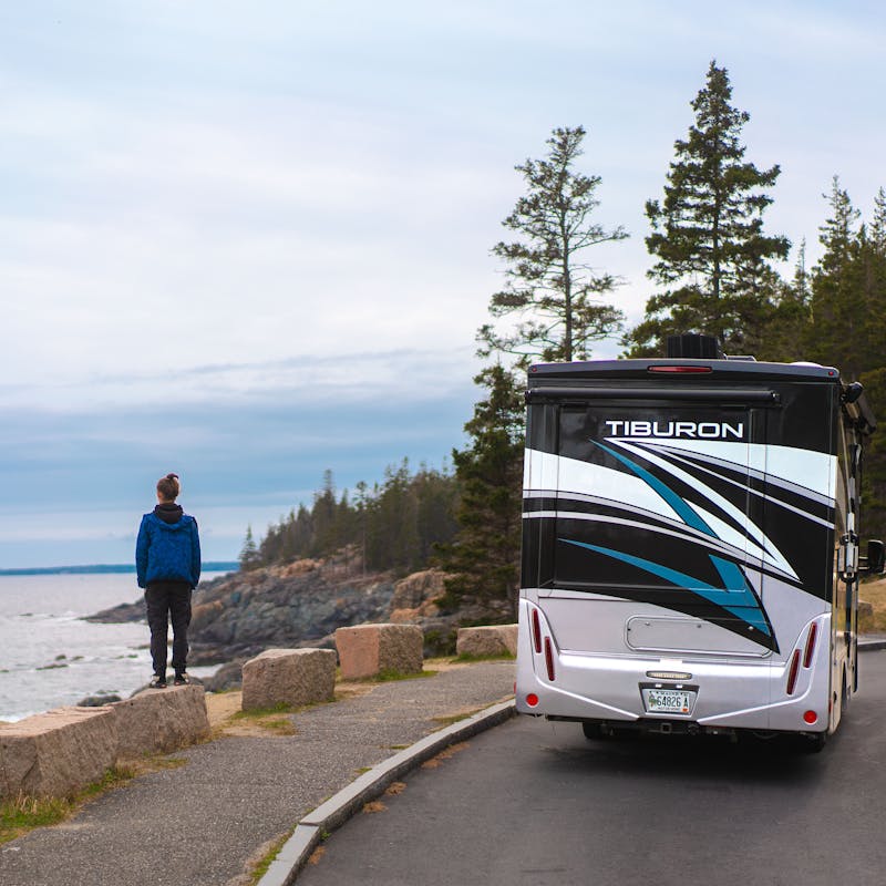 One of the Tilby kids stands at an overlook in Maine next to a rented motorized RV.
