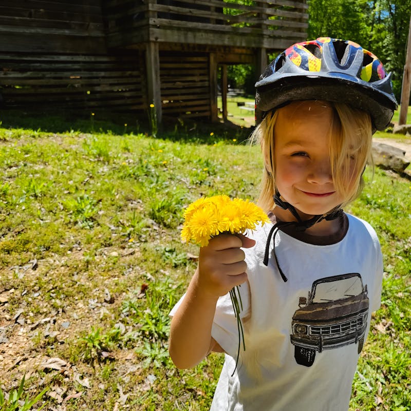 One of the Barringer's kids holds dandelion flowers.
