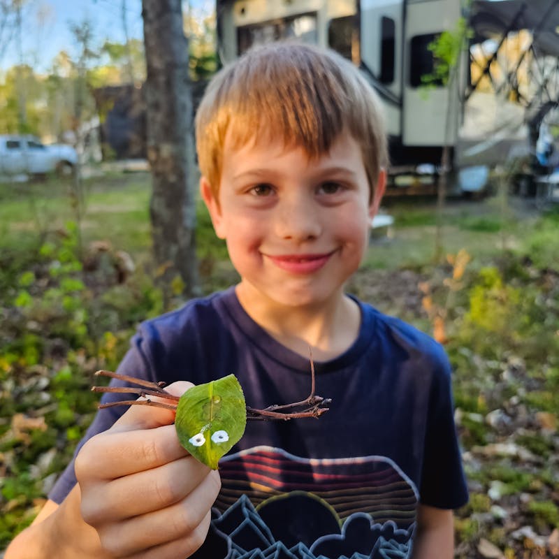 One of the Barringer kids holds a leaf insect craft next to his KZ Durango Gold fifth wheel.