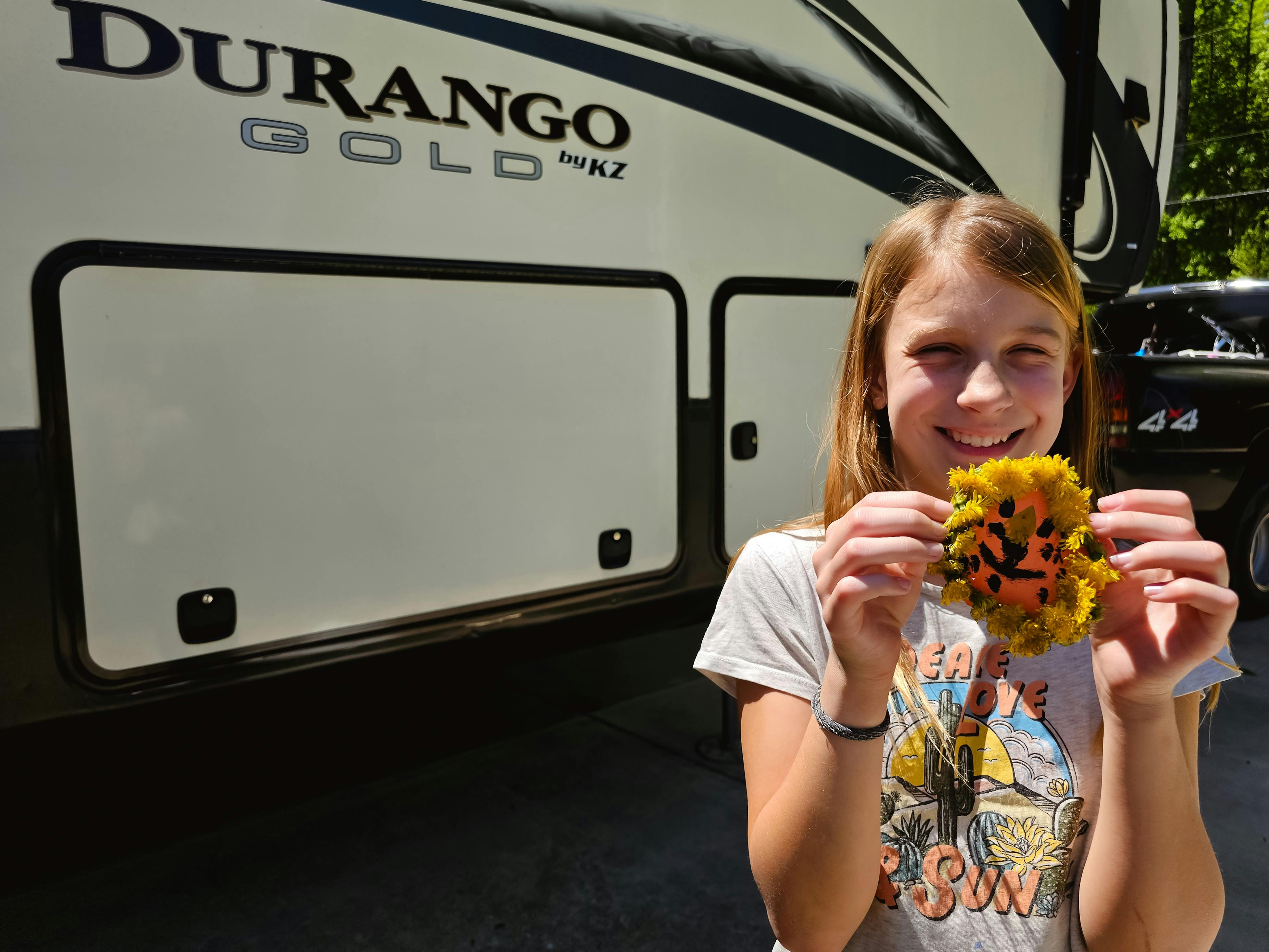 One of the Barringer kids showing off her dande-lion craft next to her KZ Durango Gold fifth wheel.