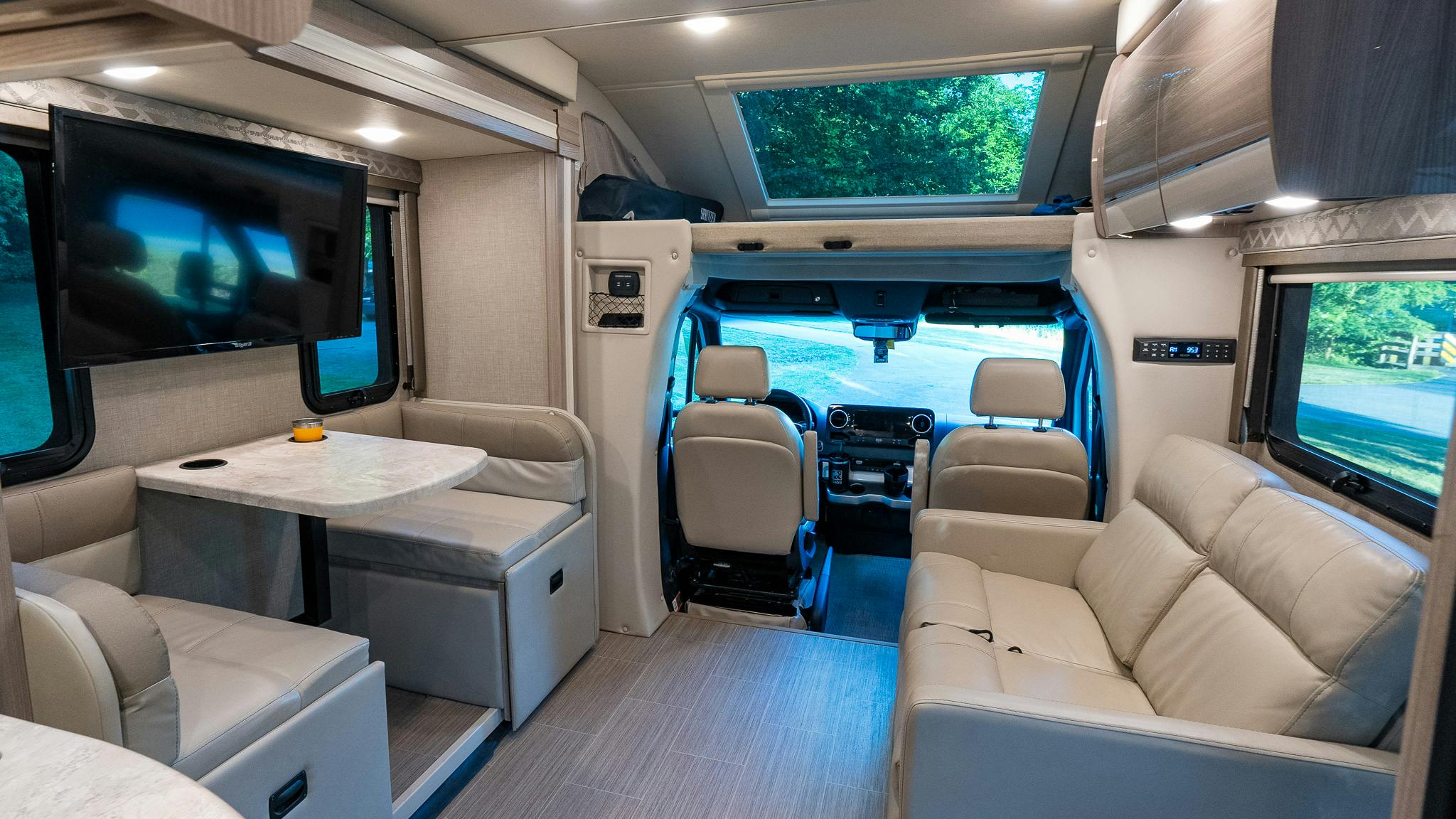 The dinette, cockpit, overhead bunk, and couch inside the Rivero's Thor Motor Coach Delano Class C Motorhome.