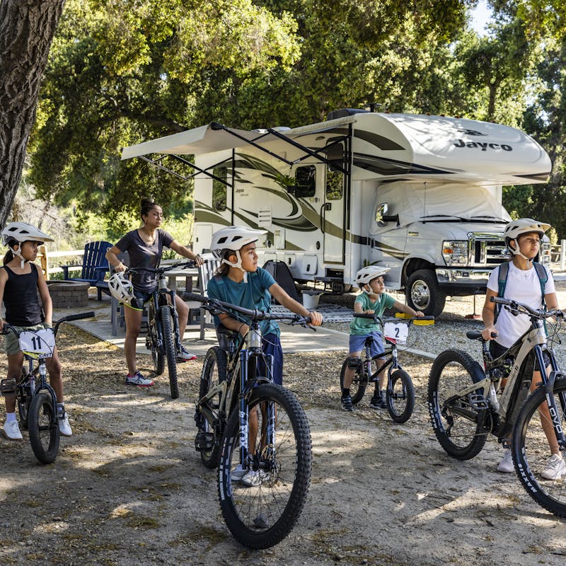 The Peña pose outside of their Jayco Greyhawk on bikes.