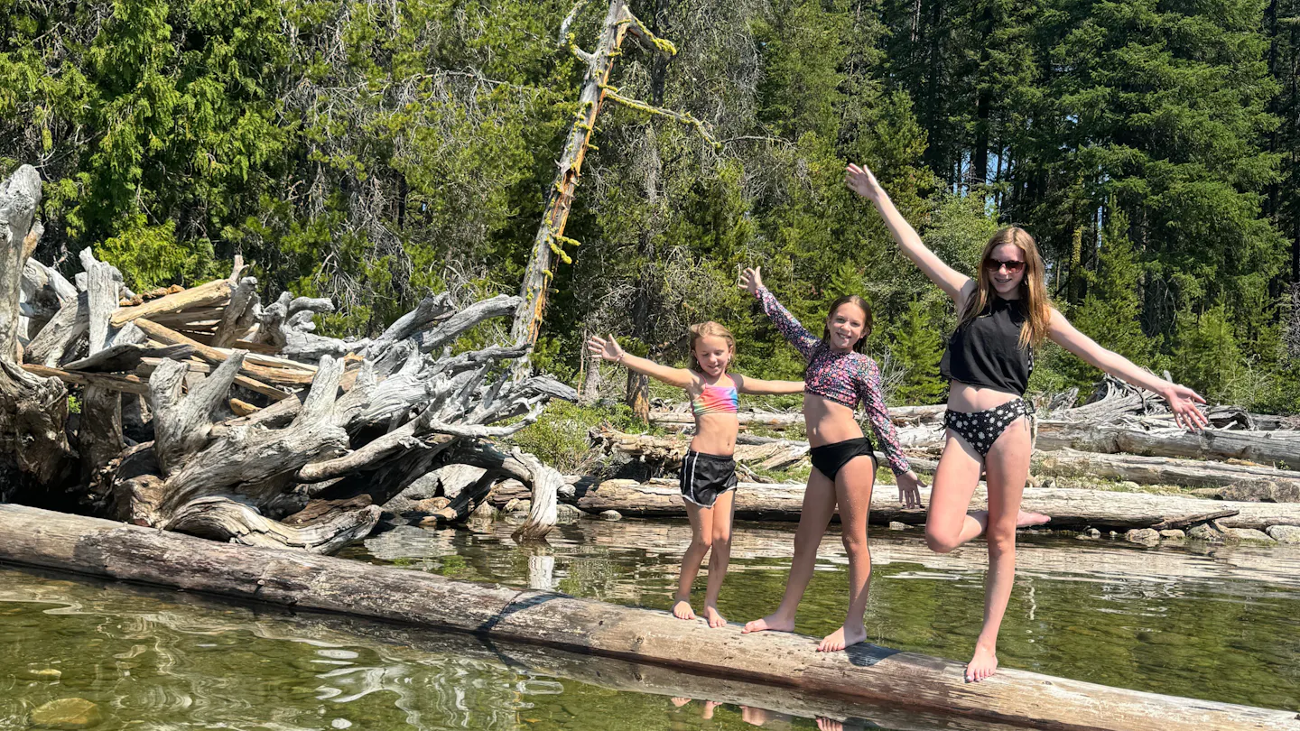 Ashley Peeples daughters posing on driftwood in Lake Wenatchee State Park.