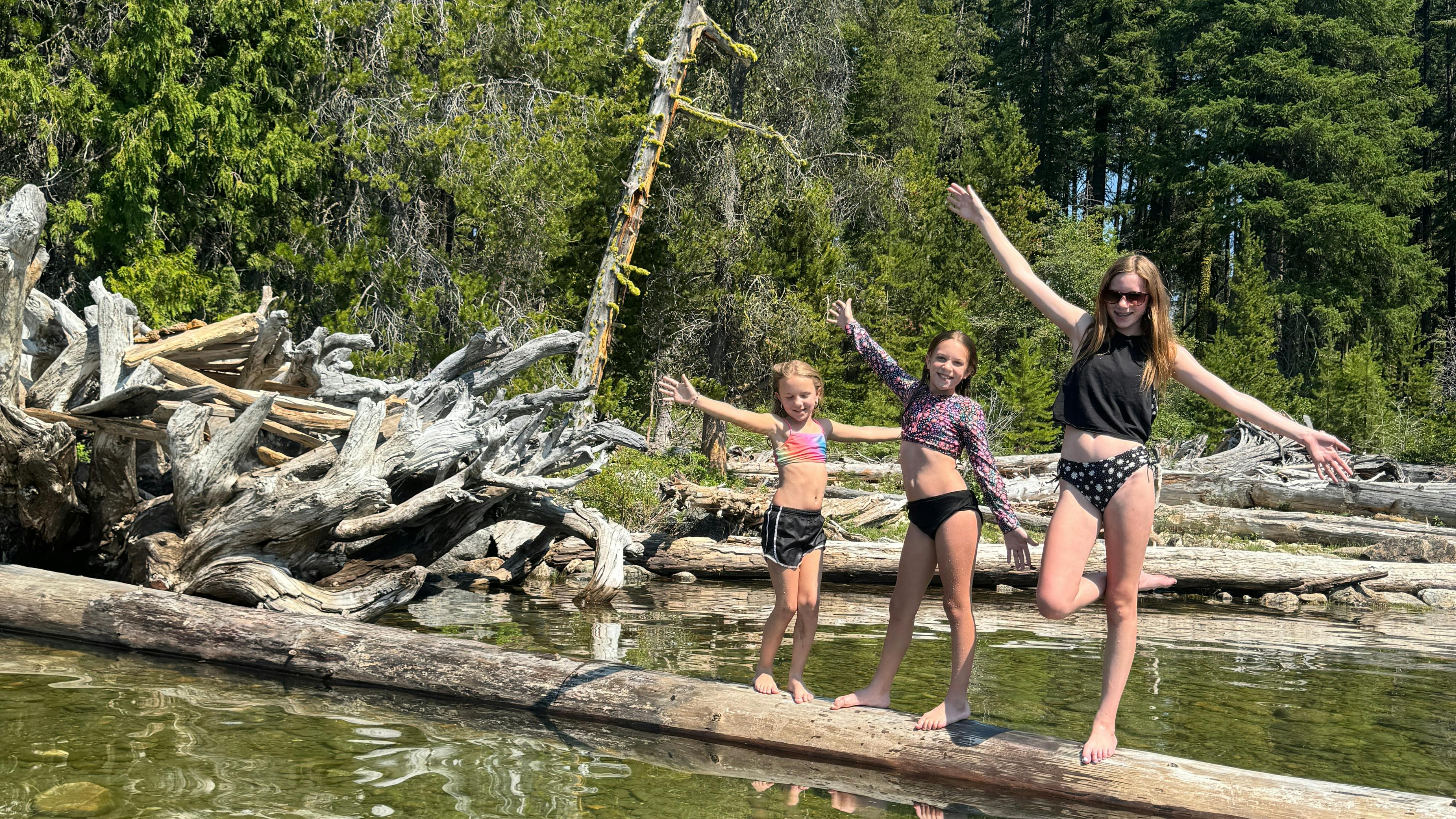 Ashley Peeples daughters posing on driftwood in Lake Wenatchee State Park.