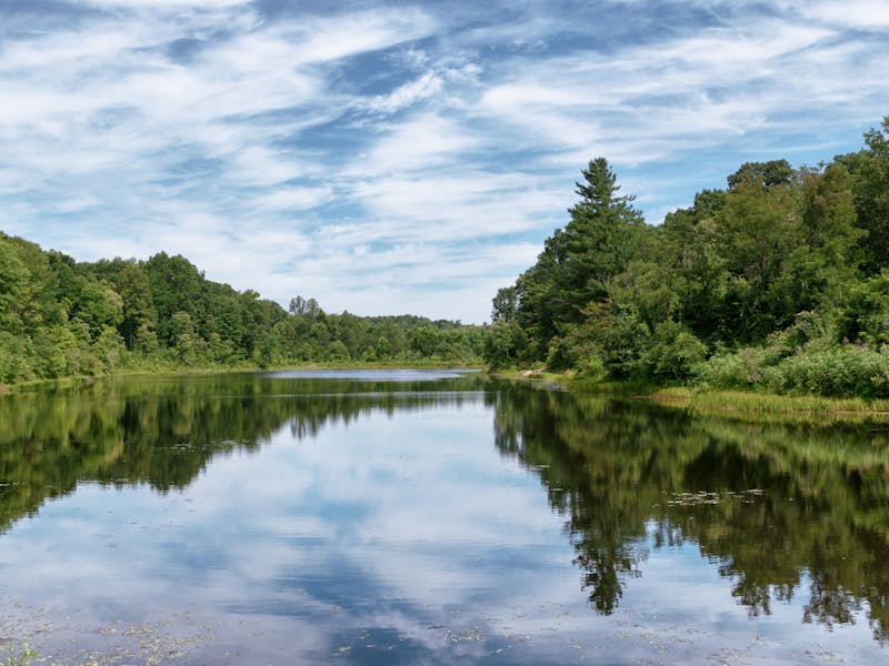 The glassy Kenton Lake and white clouds in Wayne National Forest.
