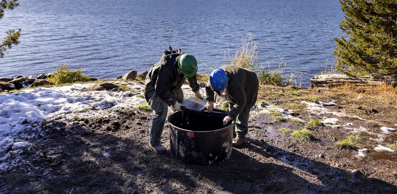 Two workers assemble a new fire ring at Diamond Lake Campground.