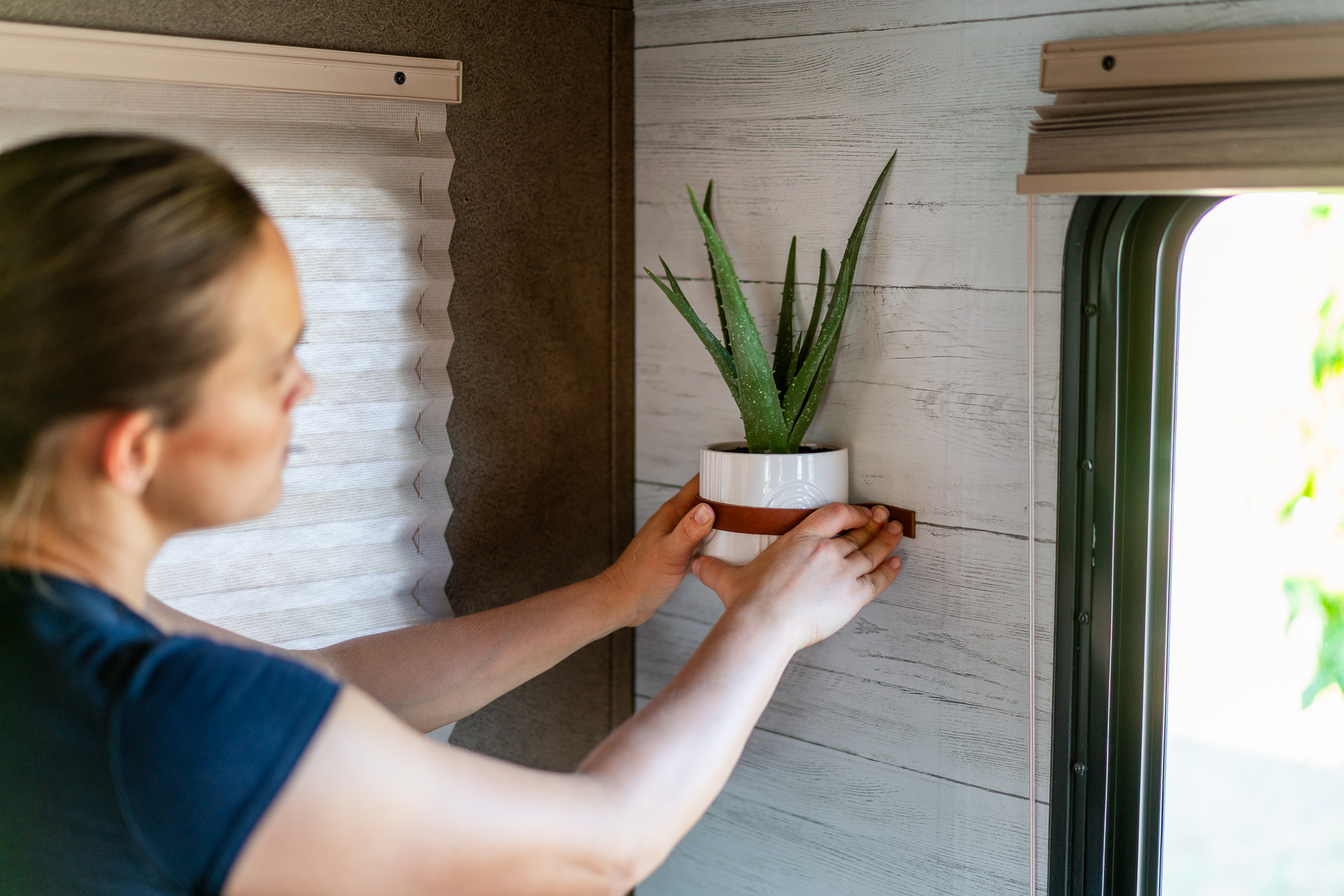 Renee Tilby hangs a wall planter inside her Jayco Jay Flight travel trailer.