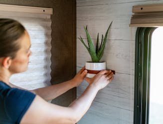Renee Tilby hangs a wall planter inside her Jayco Jay Flight travel trailer.