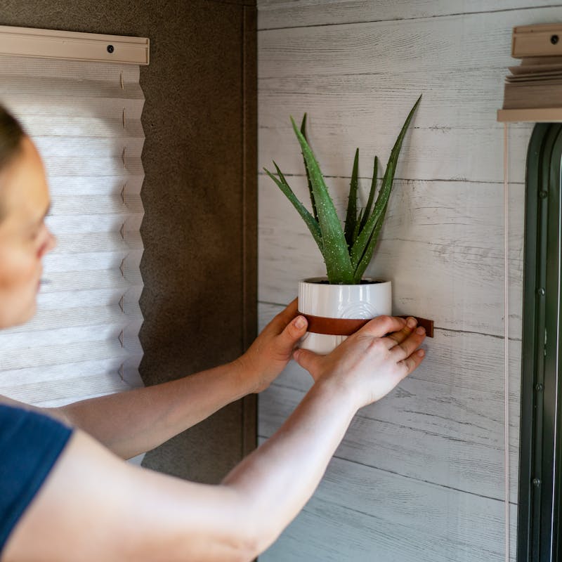 Renee Tilby hangs a wall planter inside her Jayco Jay Flight travel trailer.