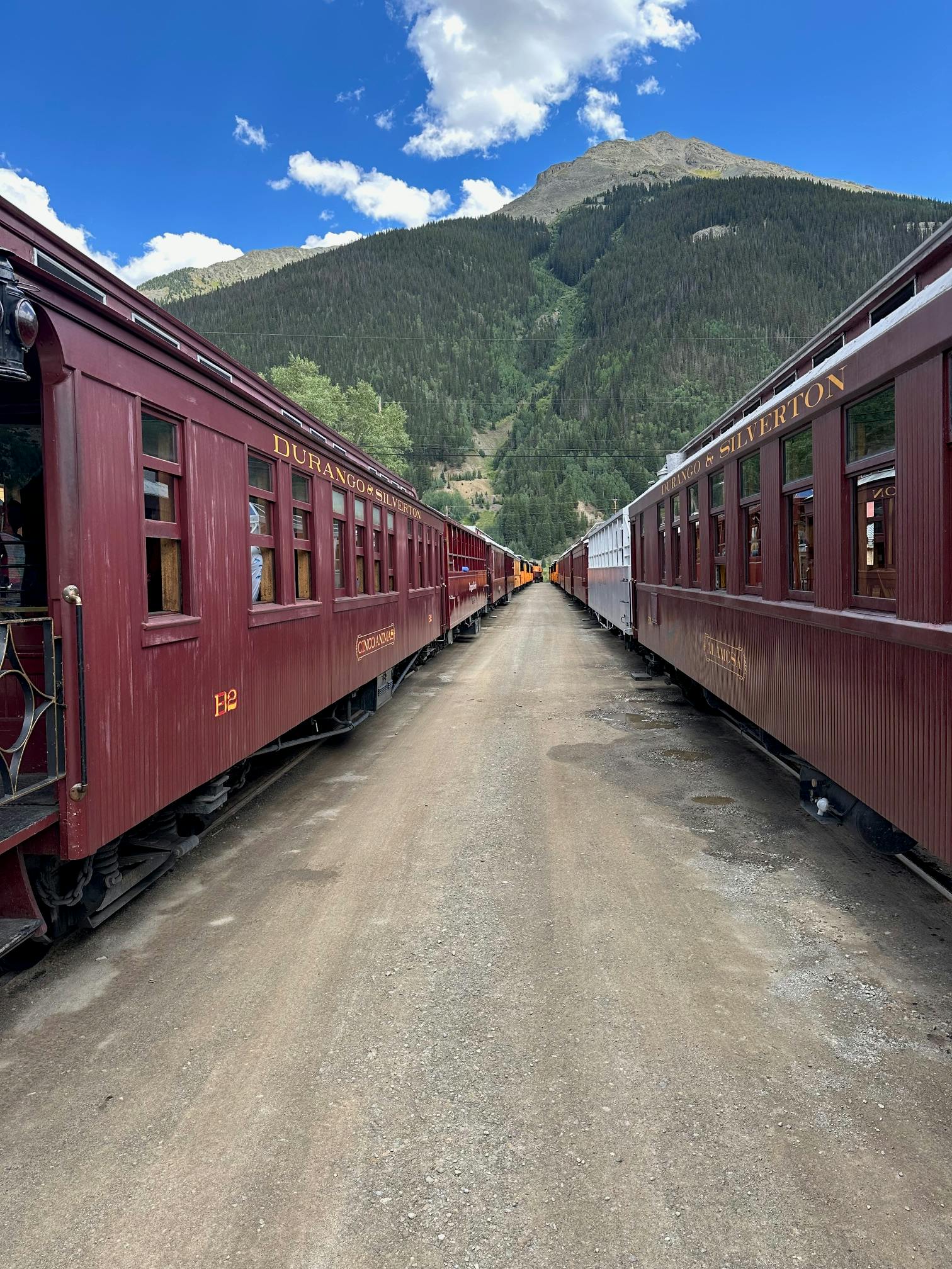 Old trains stationed amongst mountains in San Juan National Forest.