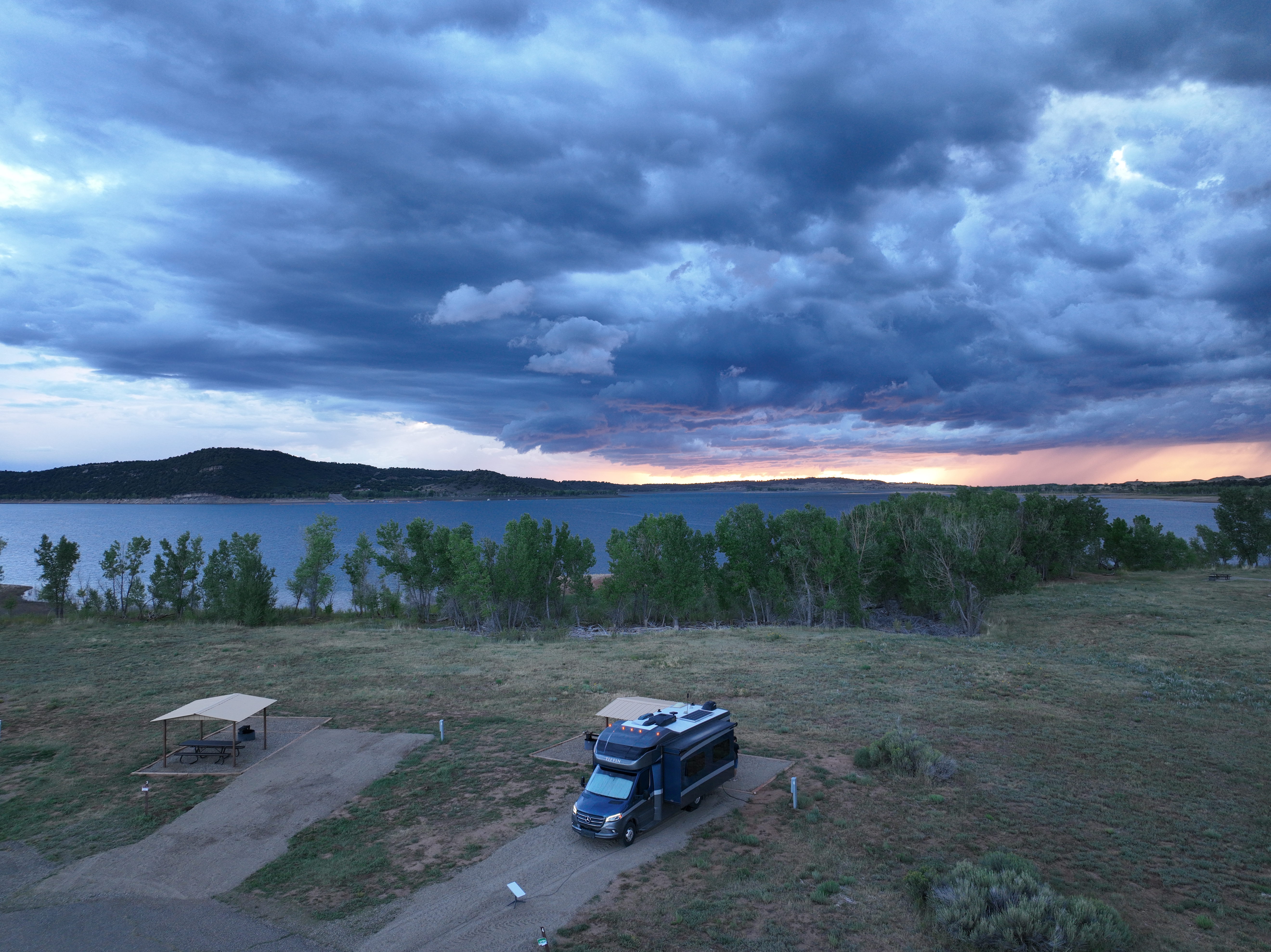 Sarah and Dustin Bauer's Tiffin Wayfarer parked at McPhee Recreational Area and a sunset peeking through the mountains.