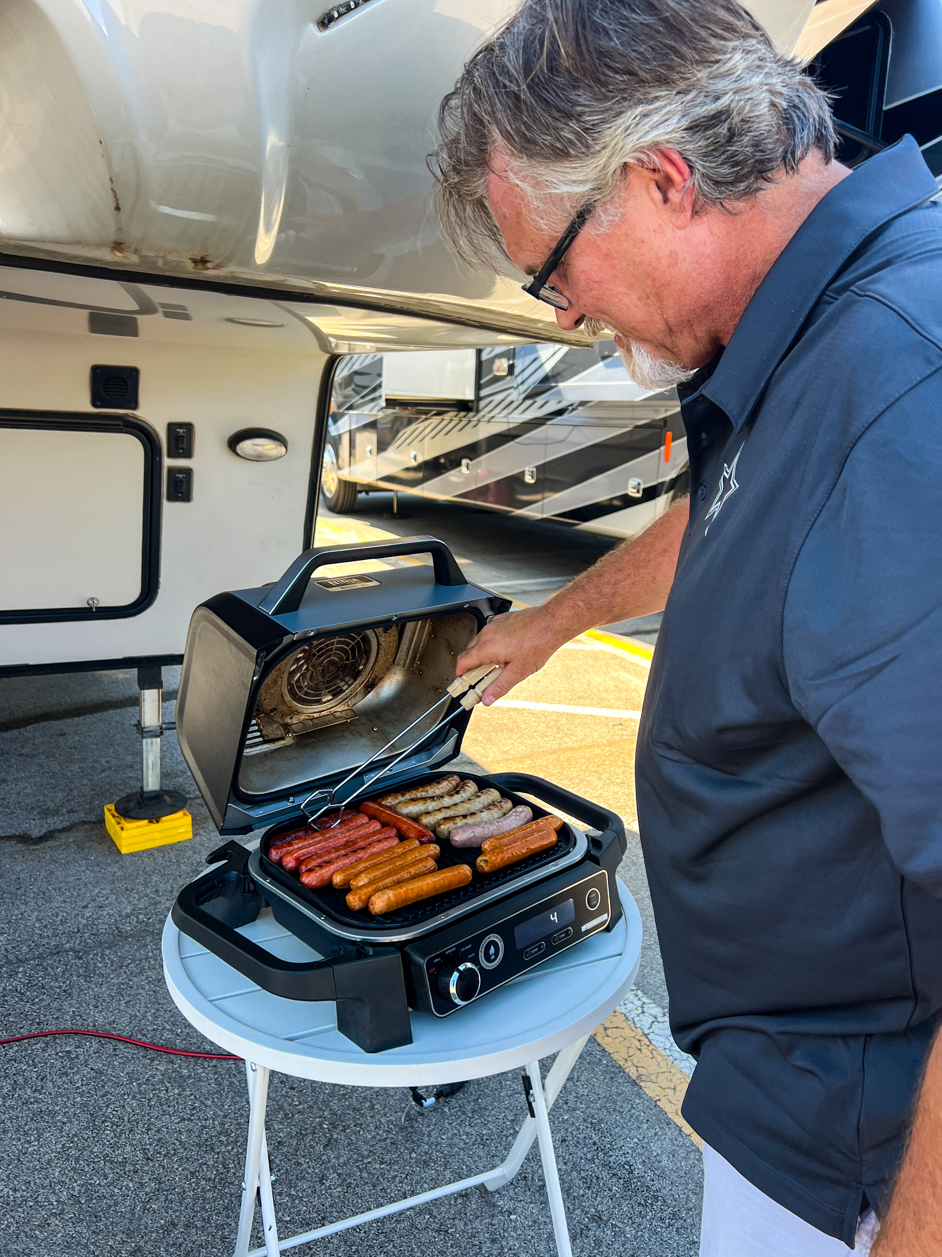 Donny Benedict grilling hot dogs next to his Keystone Cougar fifth wheel.