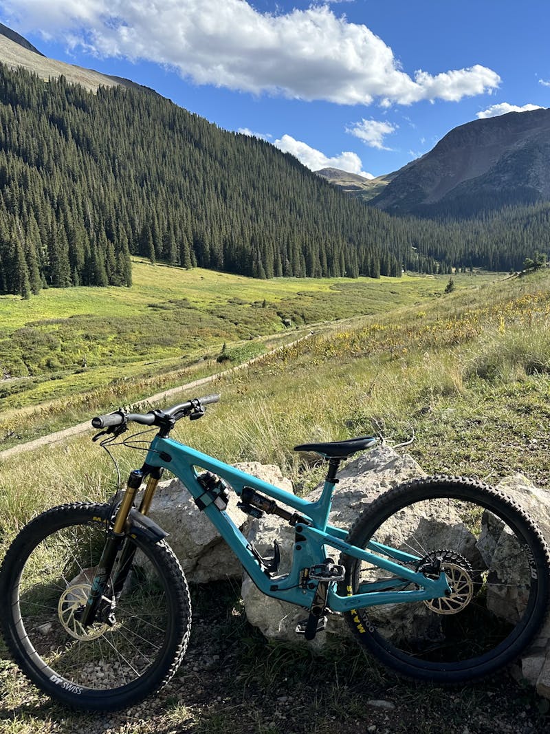 A mountain bike sits on a rock overlooking a view of mountainscapes.