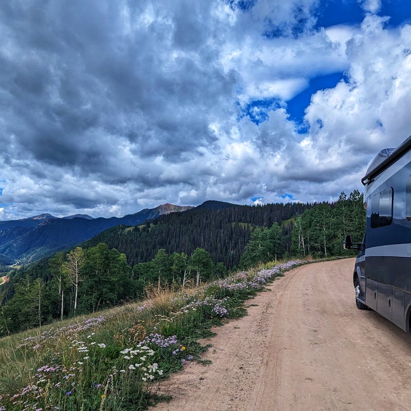 Sarah and Dustin Bauer's Tiffin Wayfarer sits on a dirt road overlooking the mountains.