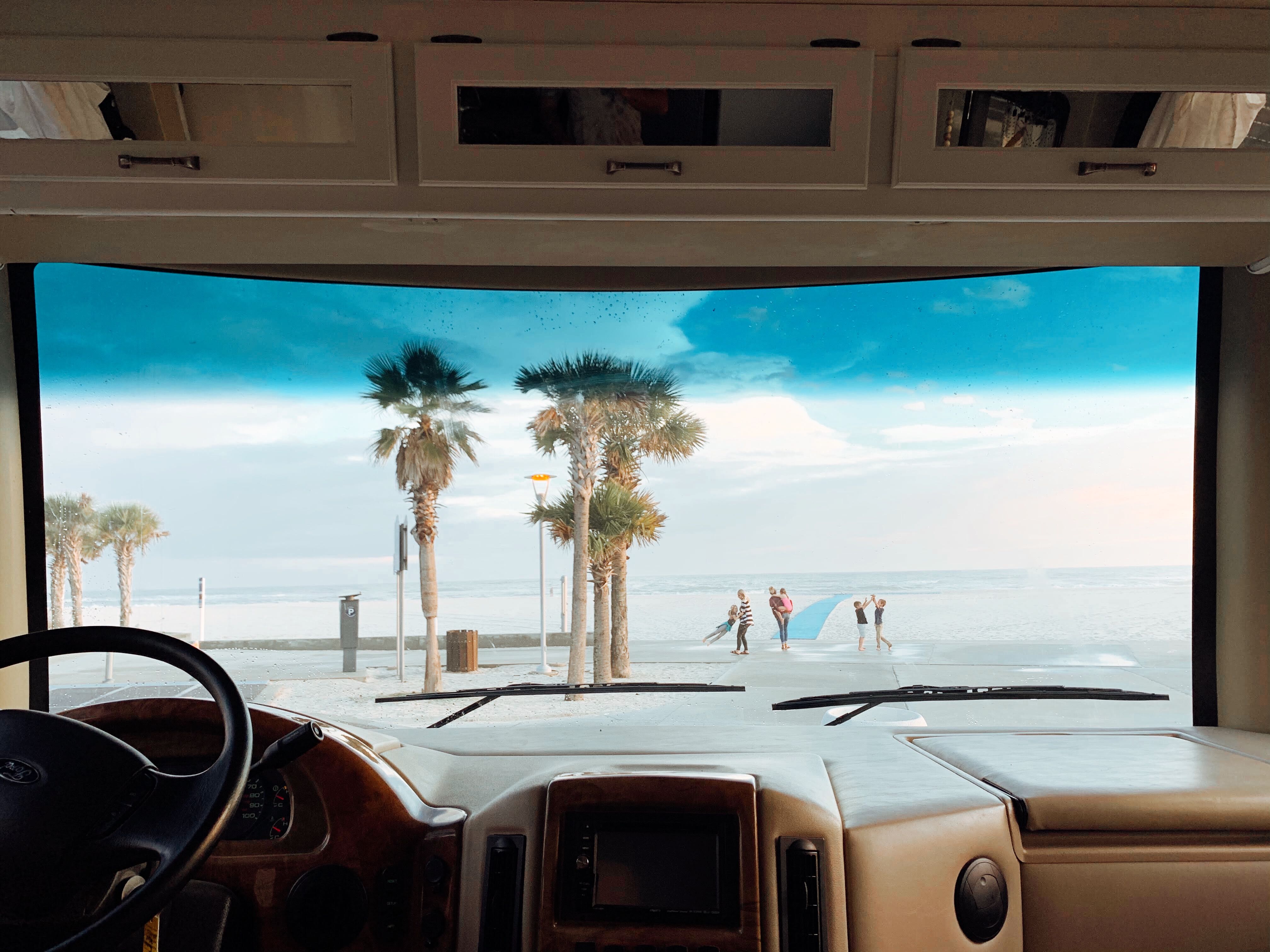 View out front windshield of palm trees, ocean, waves, and family playing in Gulf Shores, Alabama
